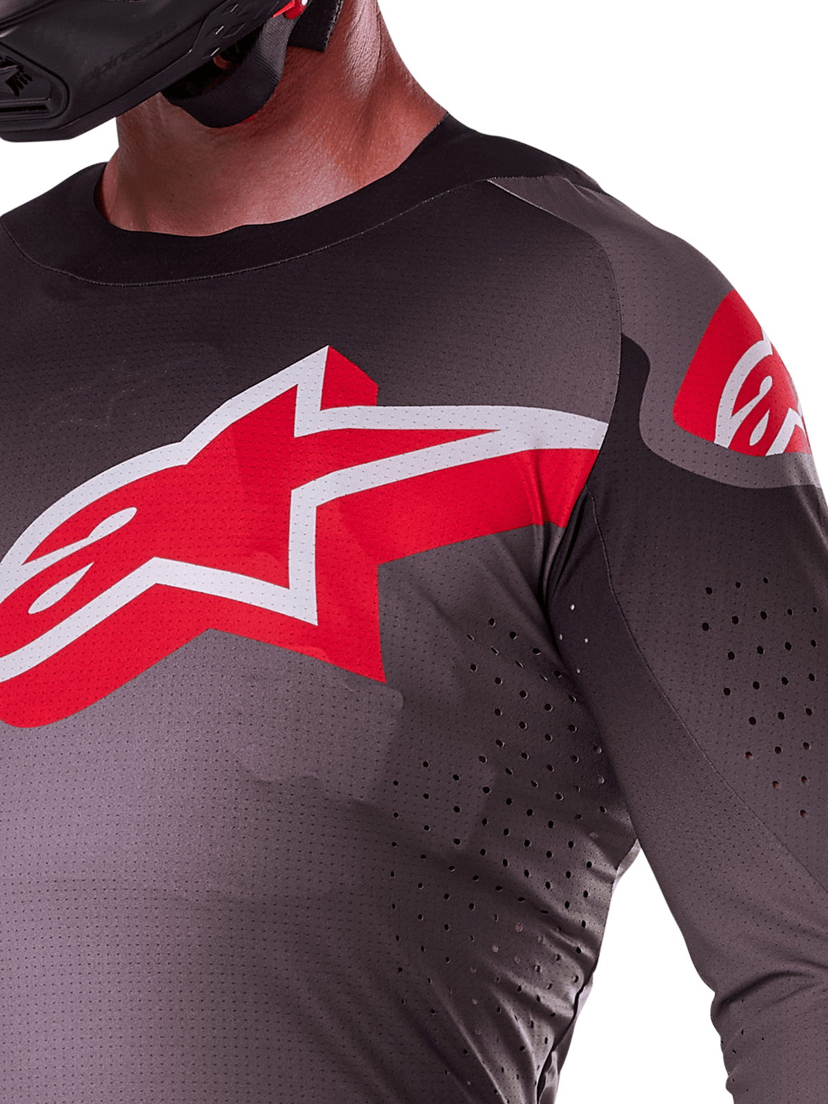 Alpinestars 2025 Supertech Lipan Trikot, Smoke Bright Red, Nahaufnahme des großen rot-weißen Stern-Logos auf der Brust, lasergeschnittene Perforationen für Luftzirkulation, leichtes atmungsaktives Material an einem Fahrer.