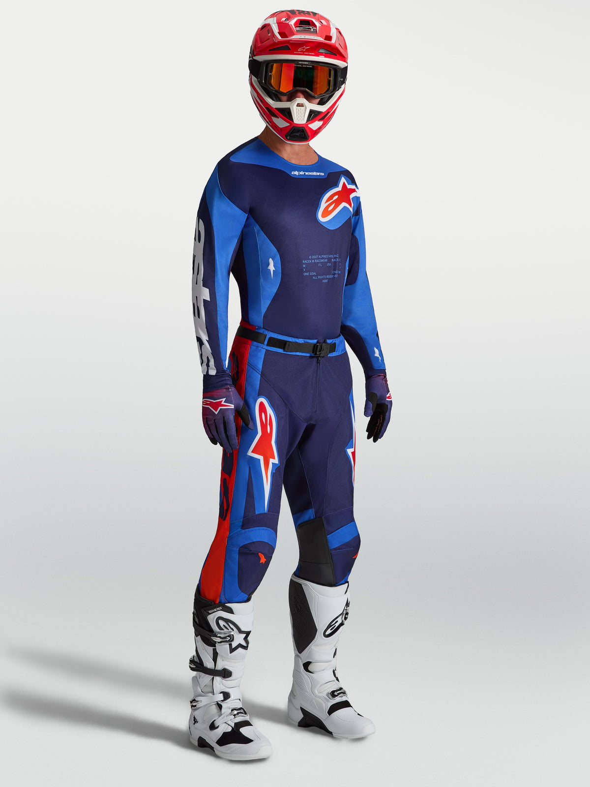 Alpinestars Racer Hunt Gear Set, blau-marineblaues MX-Ausrüstungsset mit roten Akzenten, weißen Stiefeln und rotem Rennhelm.