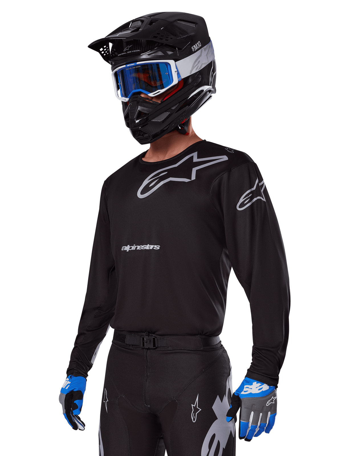 Motocross rider wearing Alpinestars 2025 Racer Graphite Gear Set, Black jersey with grey Alpinestars logos, matching black pants with grey accents, black helmet with blue and white goggles, blue and grey gloves, sleek technical outfit for off-road racing