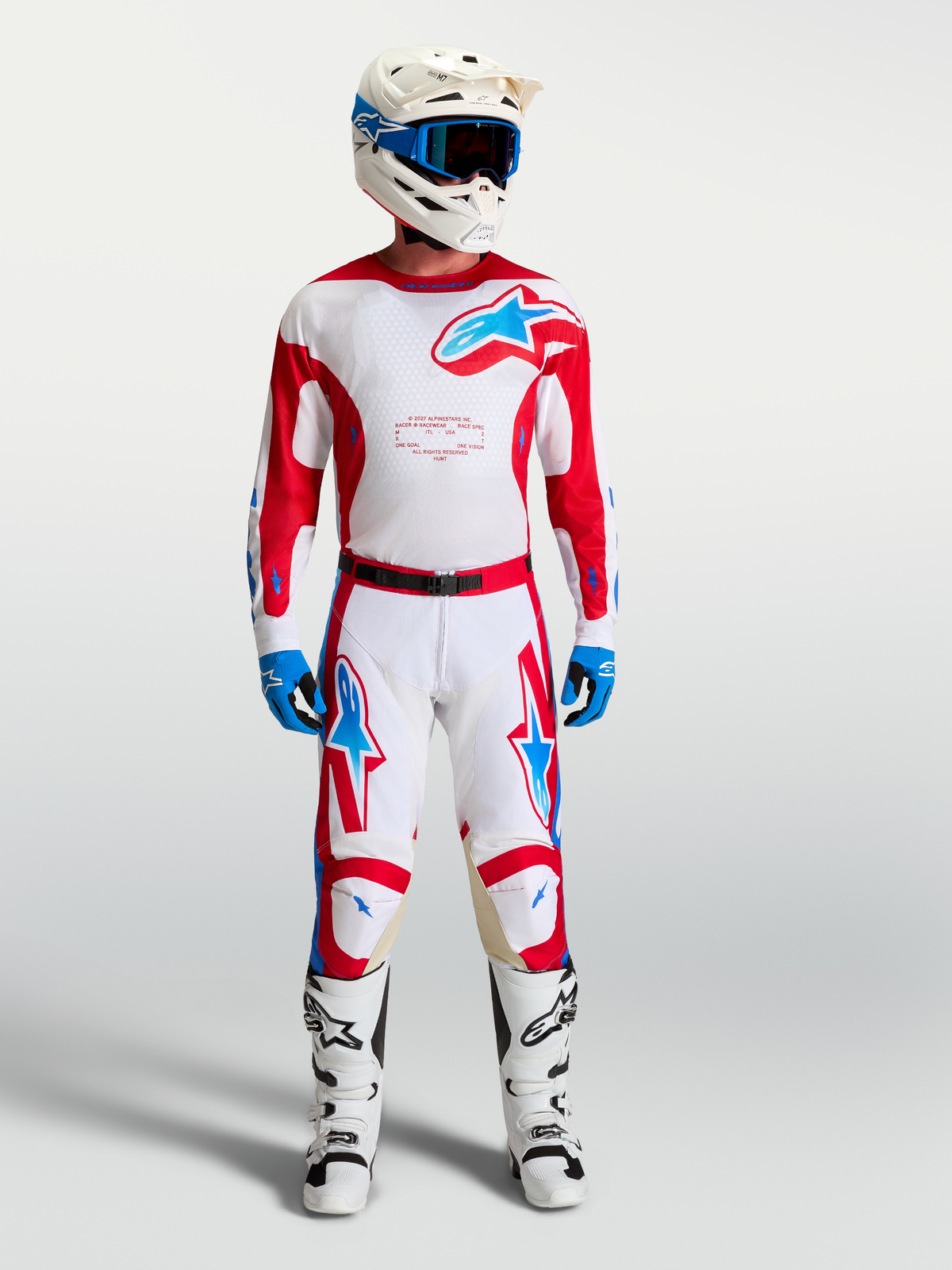 Alpinestars Racer Hose Hunt, Motocross-Hose in Weiß und Rot mit blauen Akzenten, am Model mit MX-Ausrüstung gezeigt.