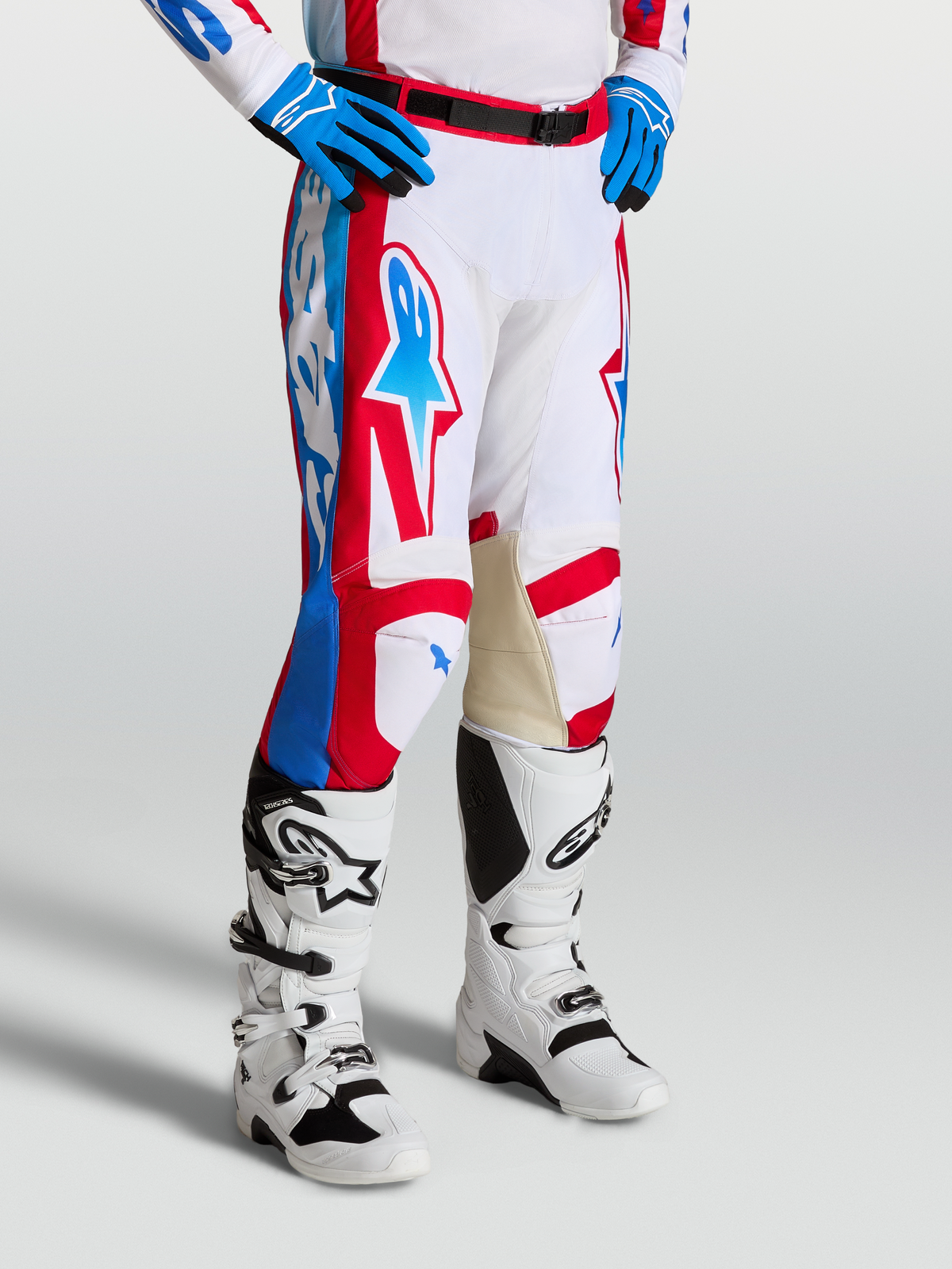 Alpinestars Racer Hose Hunt, Motocross-Rennsport-Hose in Weiß, Rot und Blau mit ergonomisch vorgekrümmten Beinen und Leder-Innenknien, getragen mit Tech 7 Motocross-Stiefeln.