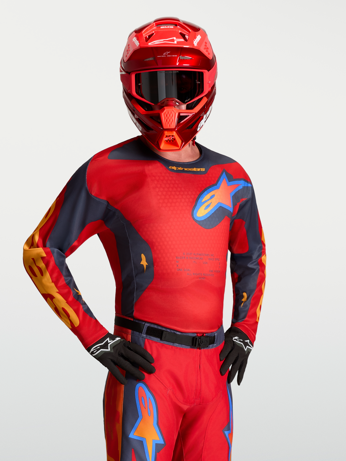 Alpinestars Racer Hunt Trikot, Motocross-Renntrikot für Herren, Rot und Grau, mit Mesh-Panels, getragen mit passendem Helm.