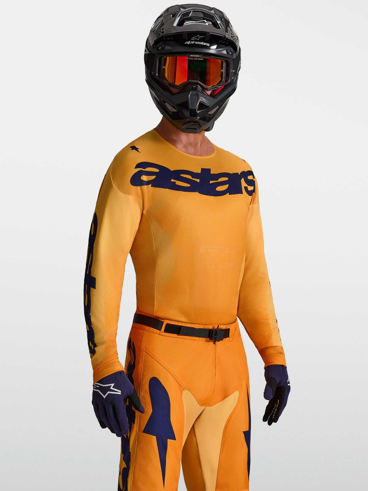 Alpinestars Racer Amber Trikot, orange-goldenes, blaues Motocross-Oberteil aus feuchtigkeitsableitendem Polygewebe am Model.