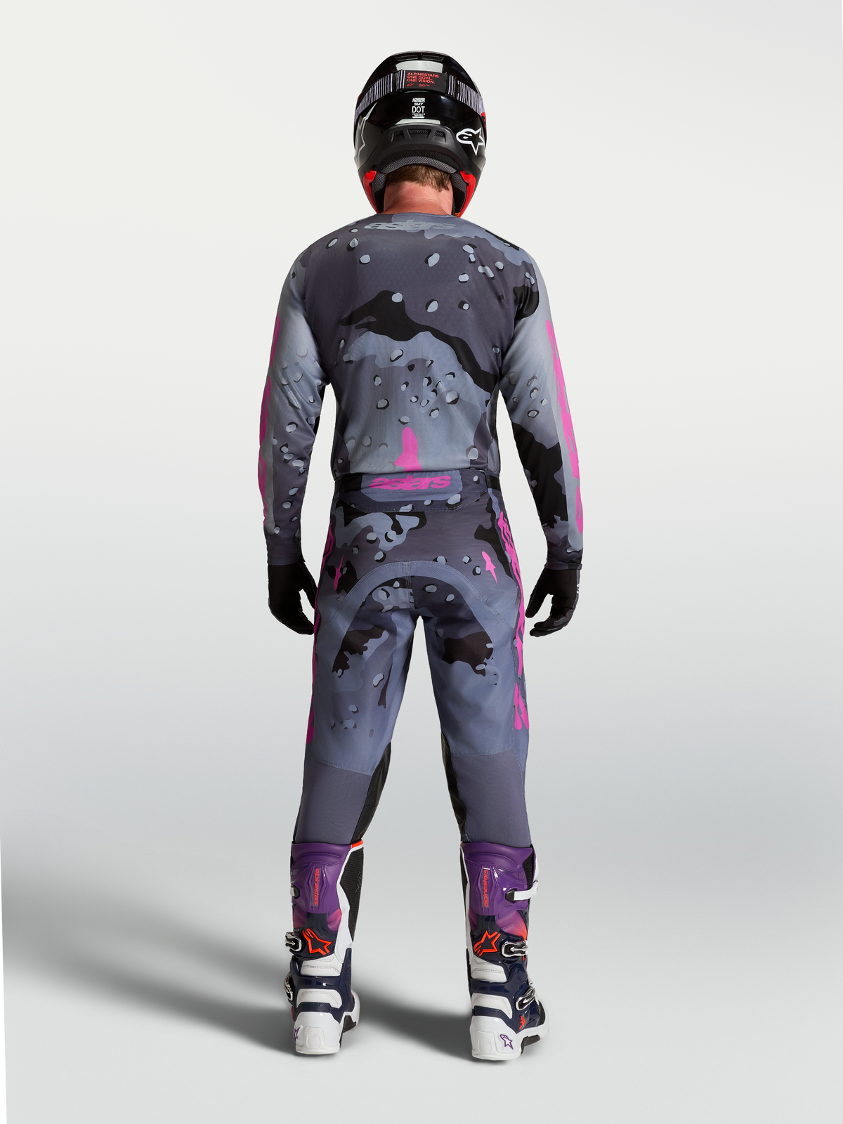 Alpinestars Racer Lone Gear Set, Motocross-Outfit, Grau-Lila Camouflage, Rückansicht des Fahrers in passender Ausrüstung.