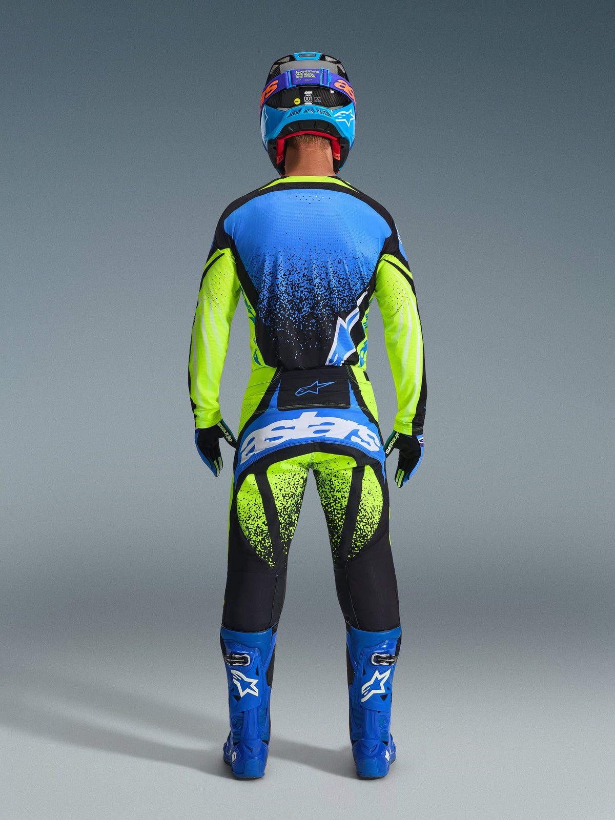 Rückansicht eines Motocross-Fahrers im 2026 Techstar Nomur Trikot in Dark Navy, Yellow Fluo und UCLA Blue, kombiniert mit einer passenden gelb-schwarzen Motocross-Hose mit „Astars“-Branding, blauen Rennstiefeln und einem abgestimmten Helm, professionelle Komplettausrüstung für den Offroad-Rennsport.