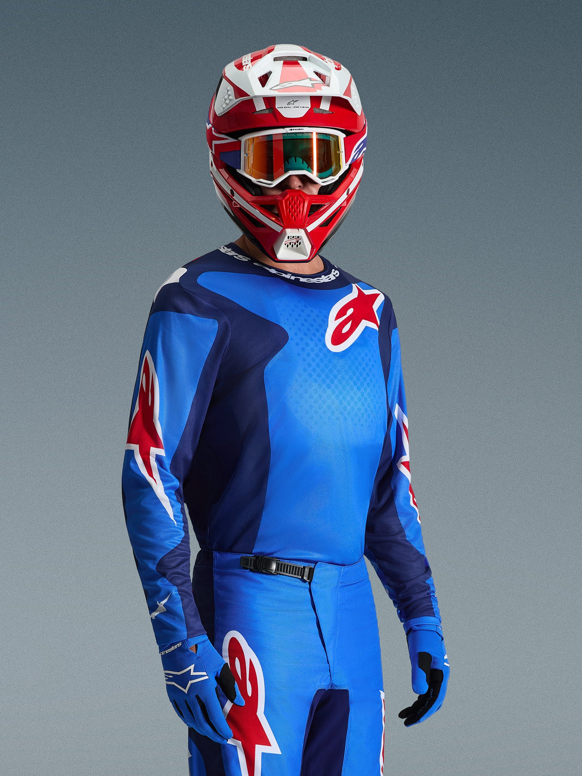 Motocross-Fahrer im Alpinestars 2026 Fluid Grid Trikot in Blau und Rot, mit roten Alpinestars Stern-Logos, kombiniert mit passender blauer Hose, blauen Handschuhen und einem rot-weißen Helm mit Schutzbrille