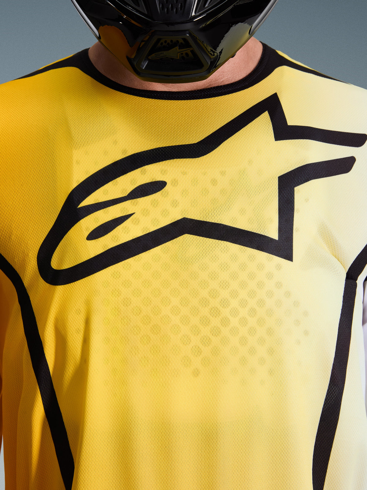 Alpinestars 2026 Fluid Apex Jersey, Motocross-Jersey, Hellgelb und Schwarz, Detailaufnahme mit einem großen schwarzen Astar-Logo auf der Brust, atmungsaktives, feuchtigkeitstransportierendes Poly-Gewebe mit Sportkragen.