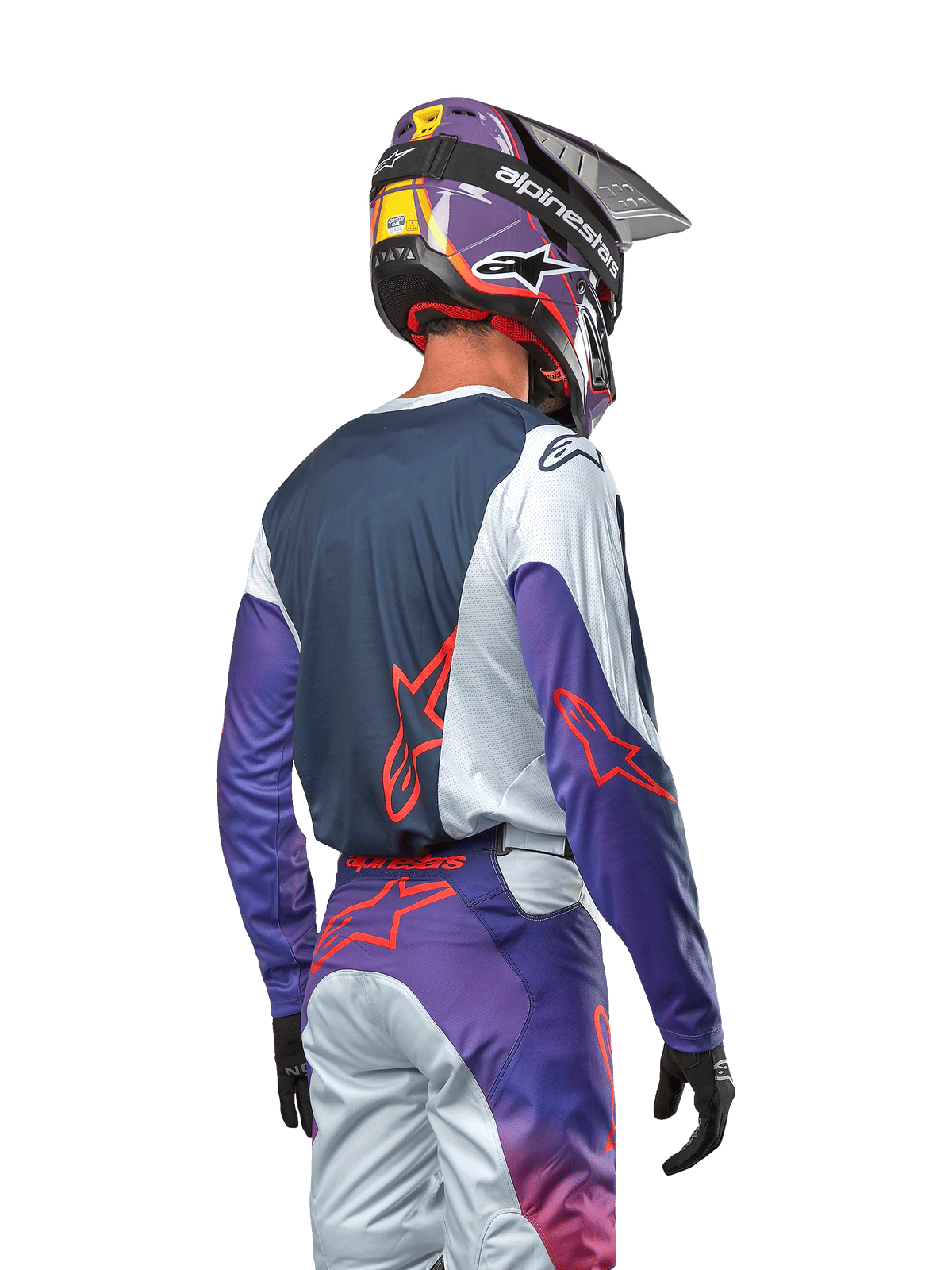 Motocross-Fahrer in der Rückansicht trägt das 2024 Racer Hoen Jersey, dunkelblaues Rückenteil mit hellgrauen Schultern und lila Ärmeln, Alpinestars-Logos in Hot Orange, passende lila-graue Hose mit lila Motocross-Helm, komplette Offroad-Rennausrüstung