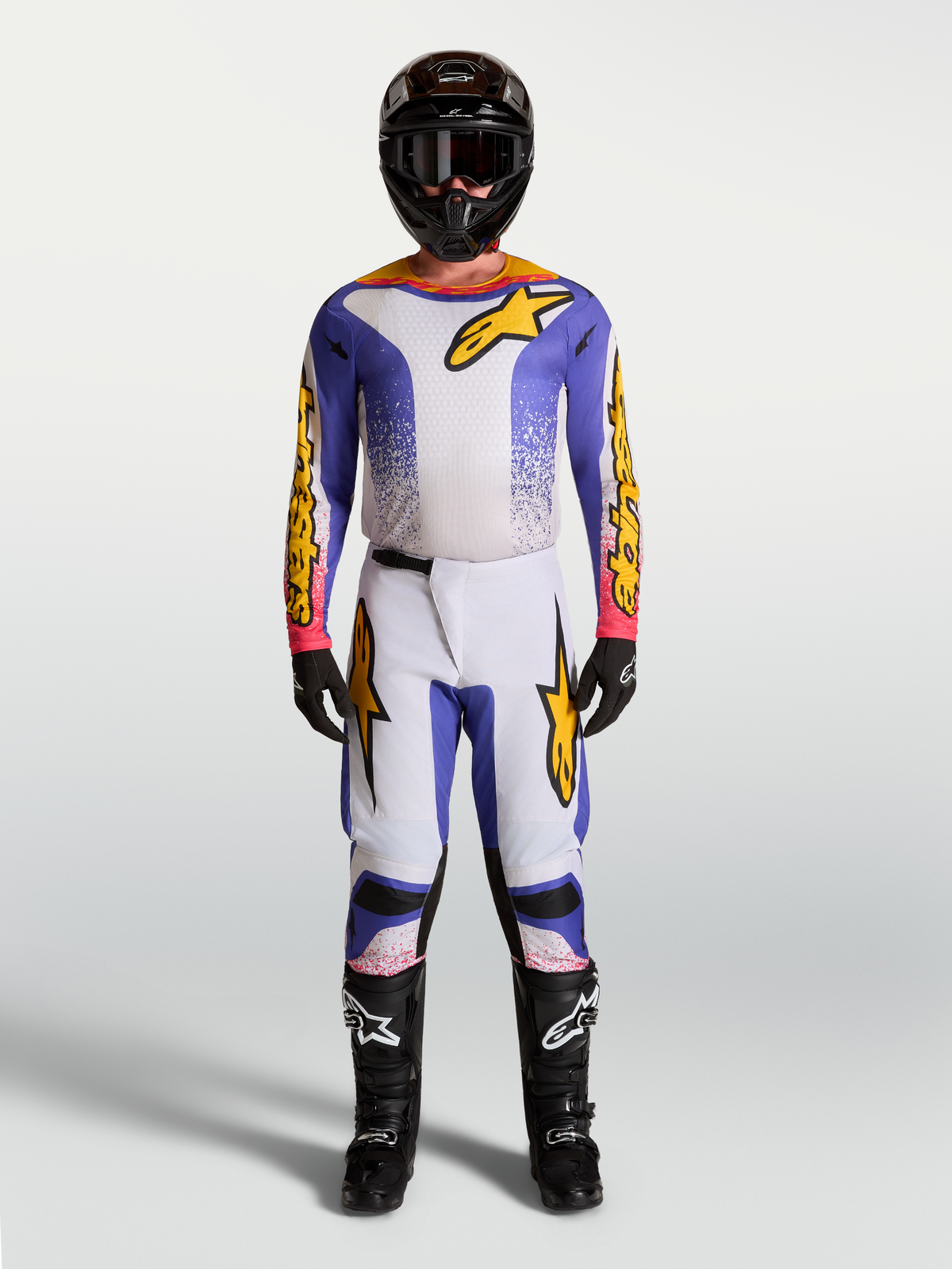 Alpinestars Fluid Drag Motocross-Set, Trikot und Hose für Herren, Lila, Blau und Gold, sportliche Passform für MX-Performance, getragen mit Helm und Stiefeln.