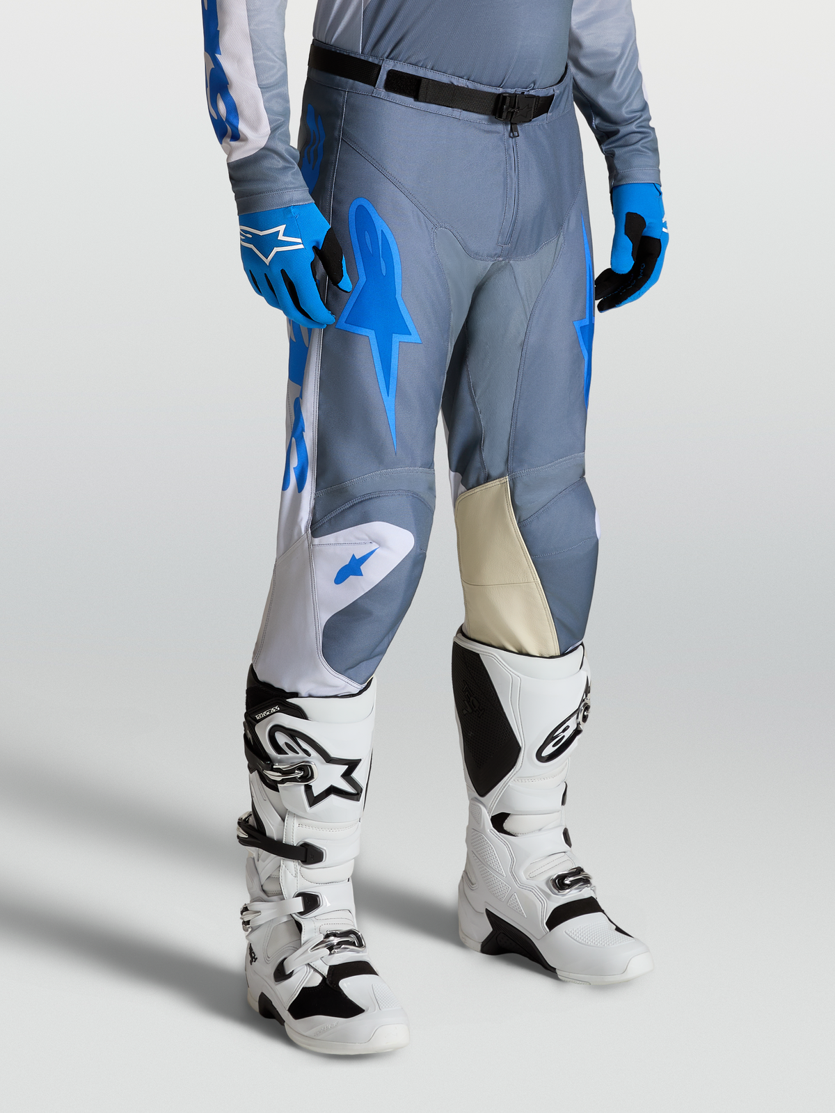 Alpinestars Racer Amber Hose, Motocrosshose für Herren, Grau und Blau, mit Knieeinsätzen aus Ziegenleder und weißen Techstar Stiefeln.