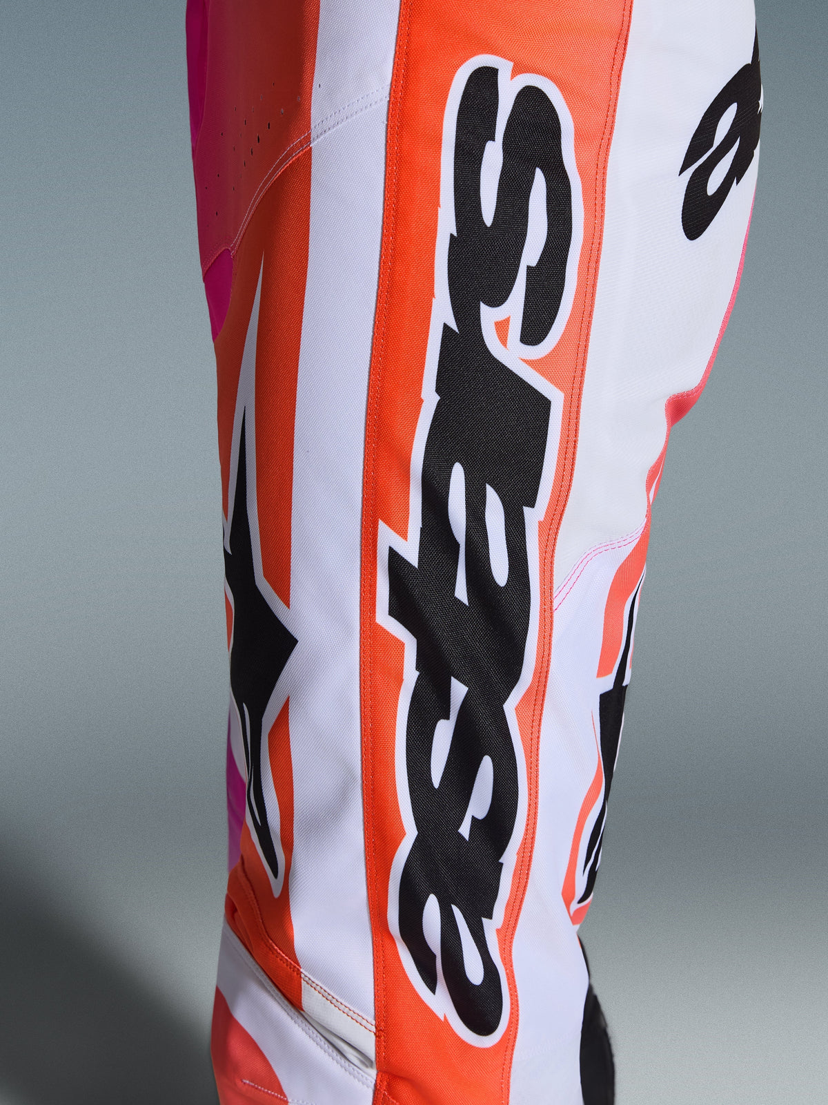 Alpinestars 2026 Racer Air Portl Hose, Motocross-Hose, Orange, Weiß und Pink, Nahaufnahme mit großem schwarzem Alpinestars-Schriftzug und Stern-Logo, perforiertes Gewebe für Belüftung, strapazierfähige Offroad-Rennbekleidung