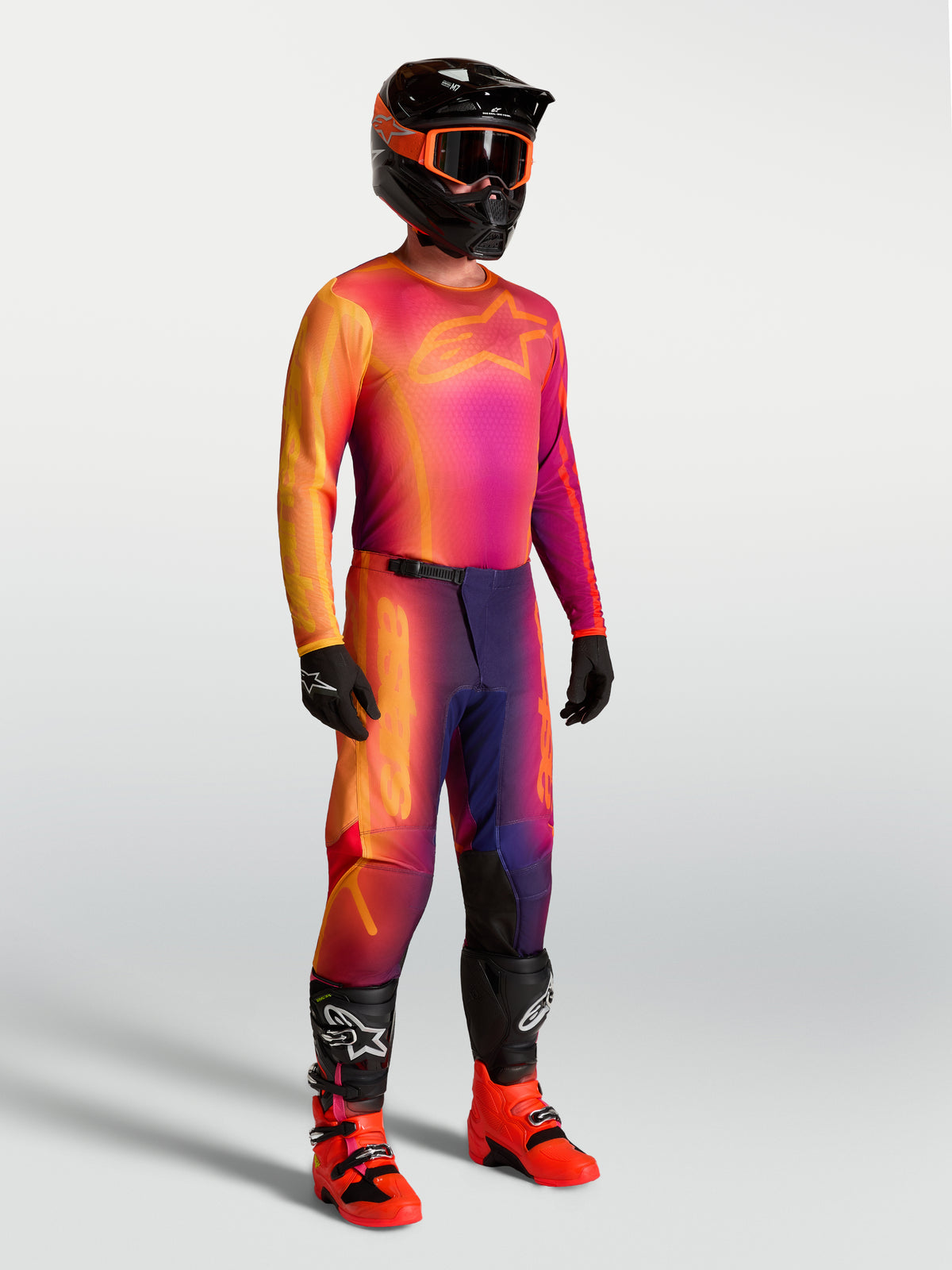 Alpinestars Fluid Kepler Trikot, Motocross-Trikot in Lila und Orange, atmungsaktives Material, getragen mit MX-Ausrüstung.