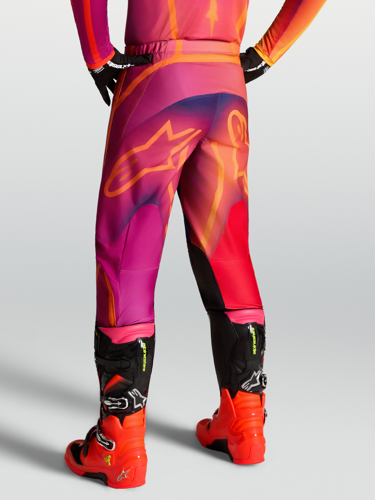 Alpinestars Fluid Kepler Hose, Motocross-Hose für Herren, Lila und Orange, 600D Polyfaser mit 3D-Musterkonstruktion, Rückansicht am Model mit Offroad-Stiefeln
