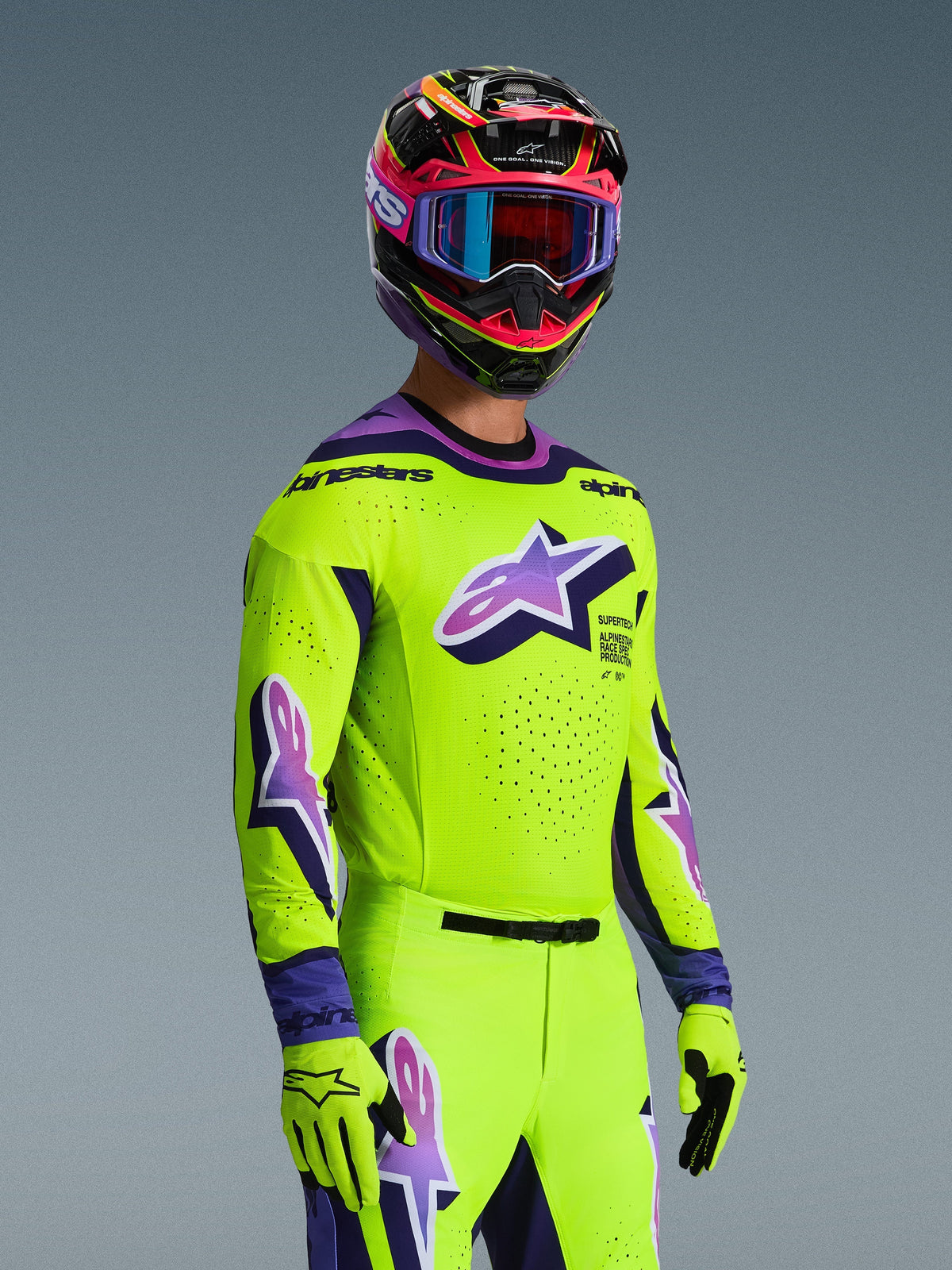 Motocross-Fahrer im Alpinestars 2026 Supertech Vista Jersey, Leuchtendes Gelb mit lila und schwarzen Akzenten, passende gelbe Hose und Handschuhe, mehrfarbiger Helm mit lila Brille, mit lasergeschnittenen Perforationen und einem großen Astar-Logo auf der Brust, abgestimmtes Profi-Rennoutfit