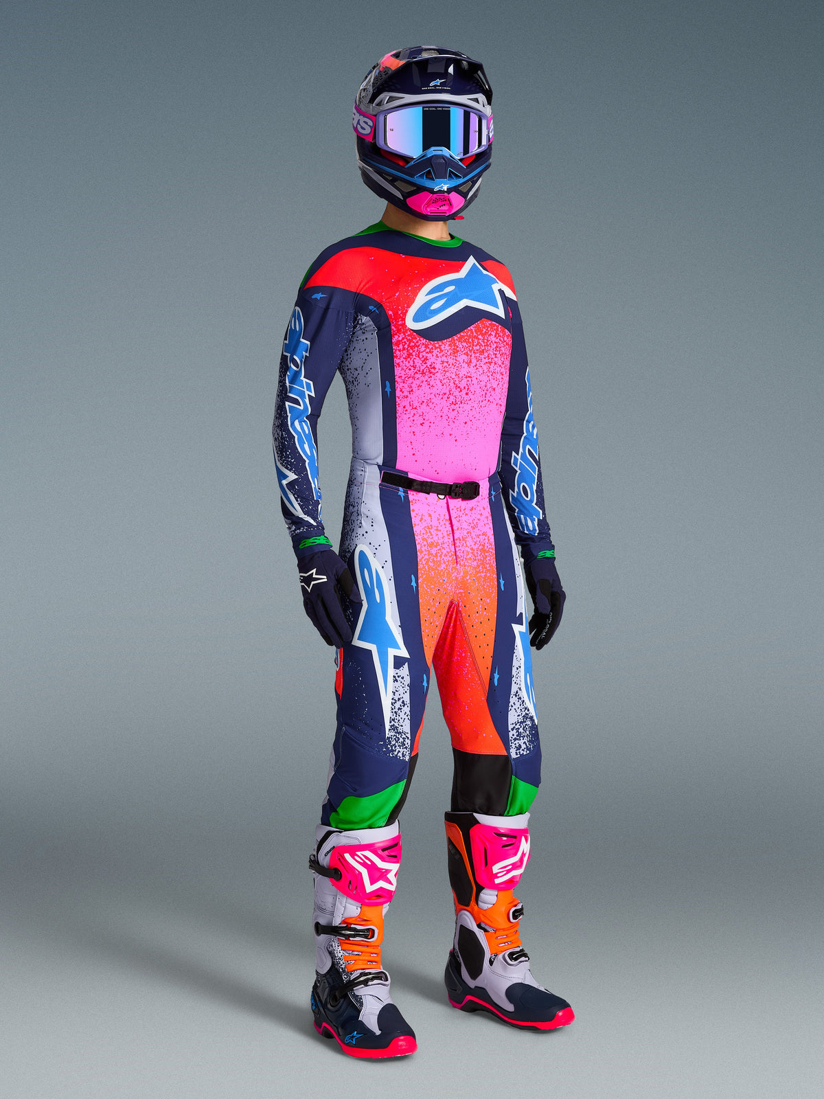 Motocross-Fahrer im Alpinestars Limited Edition Supertech Records Gear Set, mit Trikot und Hose im leuchtenden Pink-, Orange- und Dunkelblau-Farbverlauf, passend gemusterter Helm und Brille, dunkelblaue Handschuhe und abgestimmte Rennstiefel, komplette professionelle Offroad-Rennausrüstung