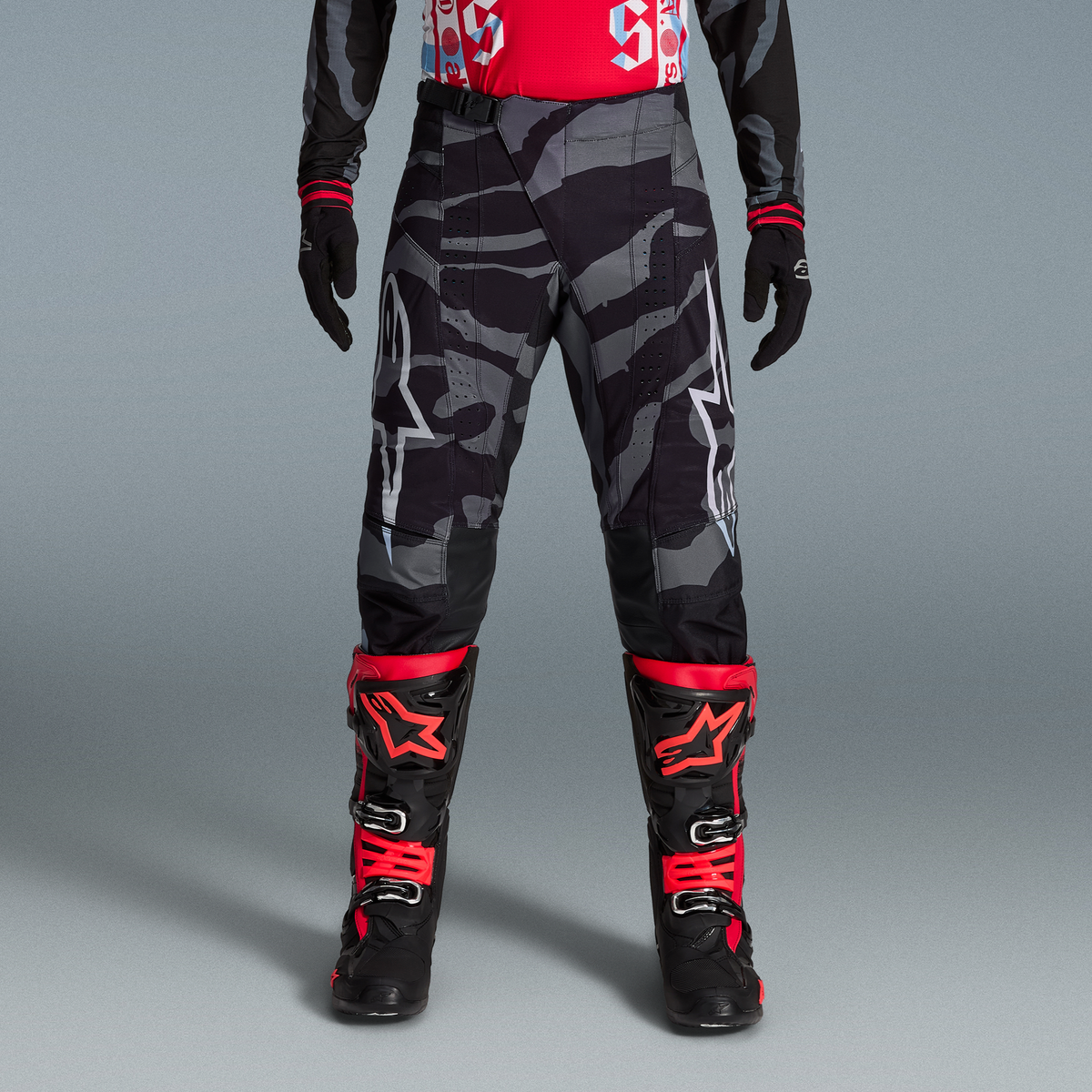 Alpinestars Techstar Beast Coast Limited Edition Ausrüstungs-Set, graue Camouflage-Hose und rot-schwarze Stiefel.