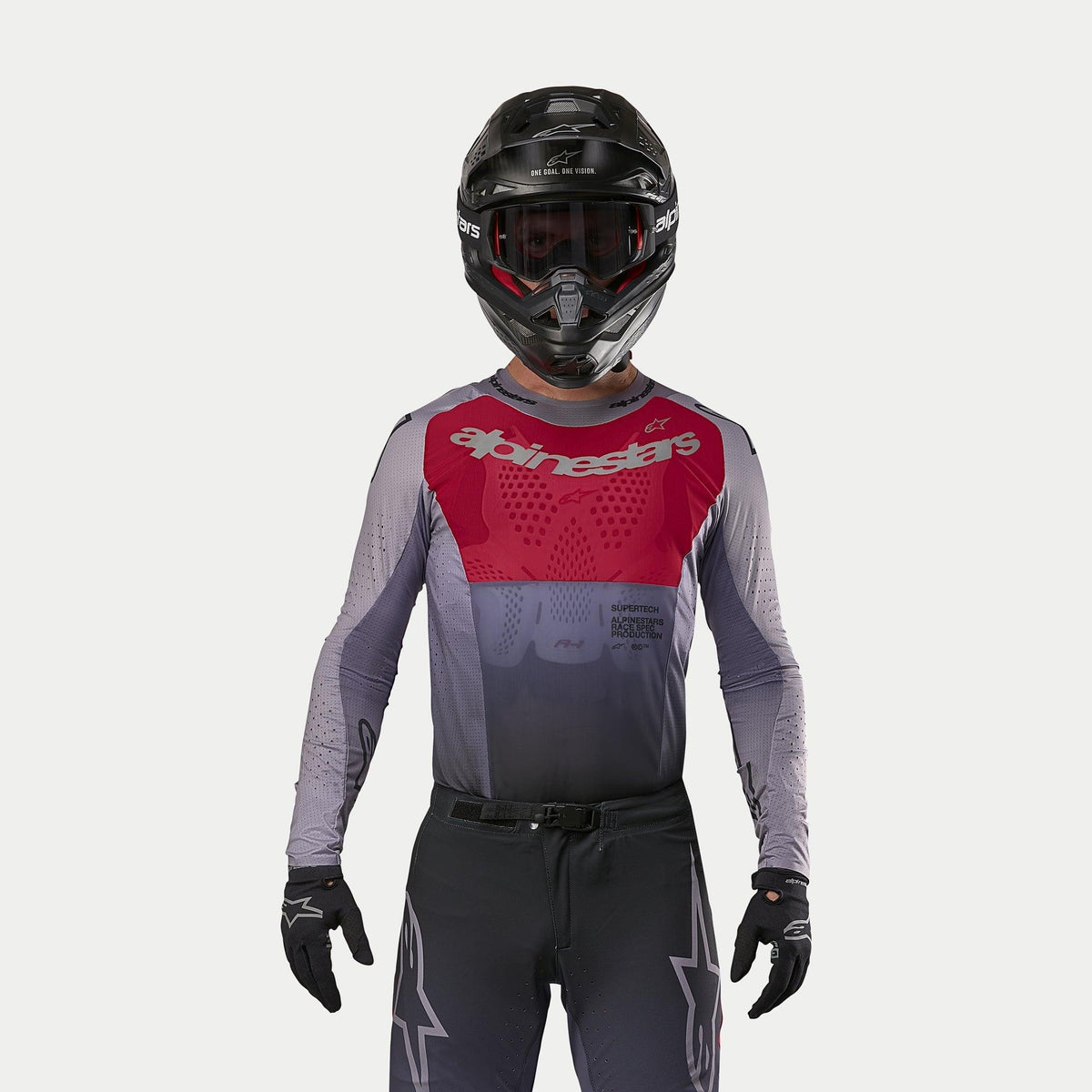 Motocross rider wearing the Alpinestars 2024 Supertech Dade Jersey in Iron Red Berry, featuring a red chest panel and gray sleeves with silver branding, worn with matching pants, a black helmet, and black gloves, professional off-road racing gear