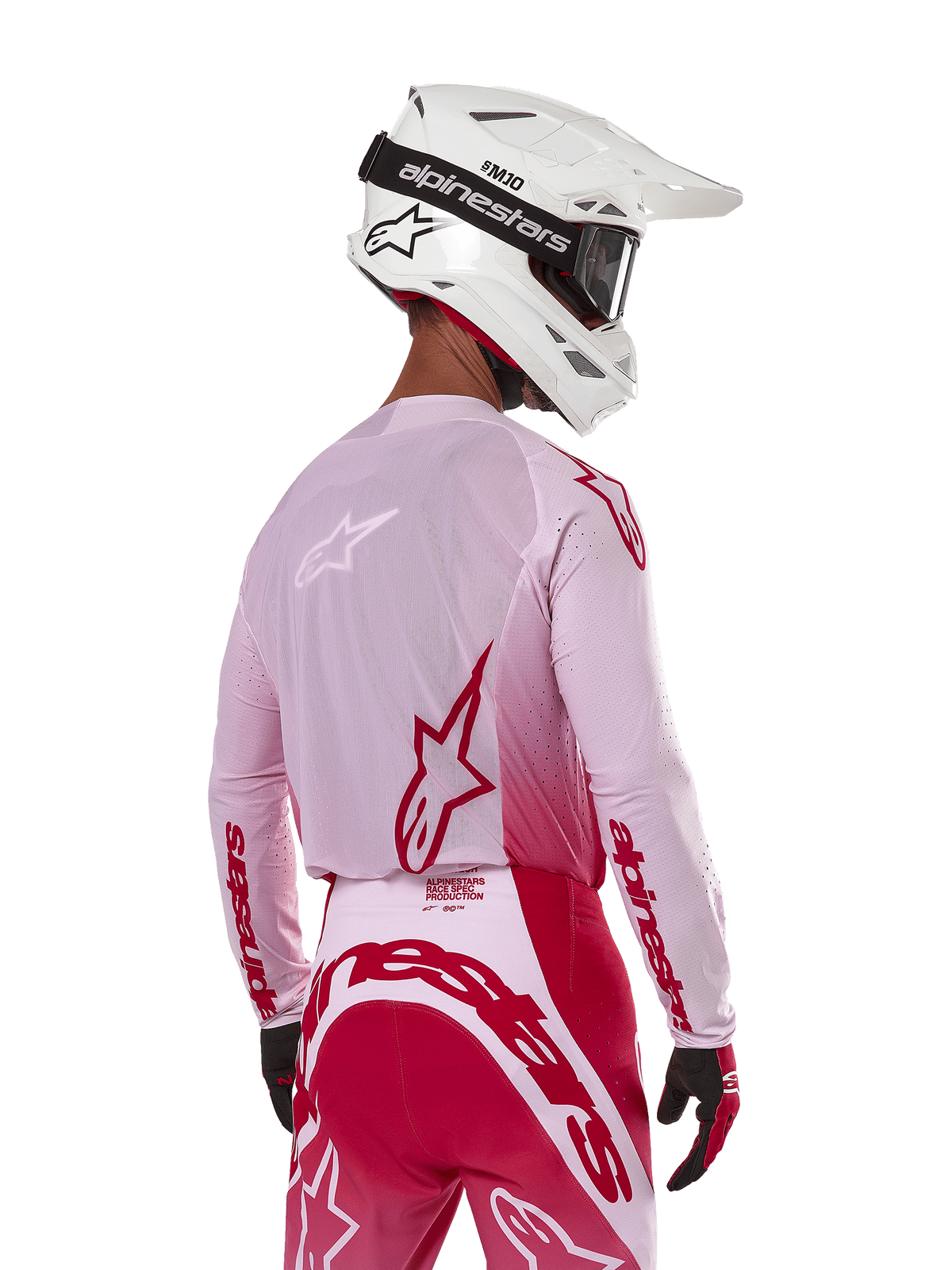 Motocross-Fahrer in der Rückansicht, trägt das Alpinestars 2024 Supertech Dade Jersey in Red Berry Lilac, mit atmungsaktiven Mesh-Panels und roten Alpinestars-Logos, kombiniert mit einer passenden rot-lilafarbenen Hose und einem weißen Alpinestars-Helm mit Brille, professionelle Offroad-Rennausrüstung