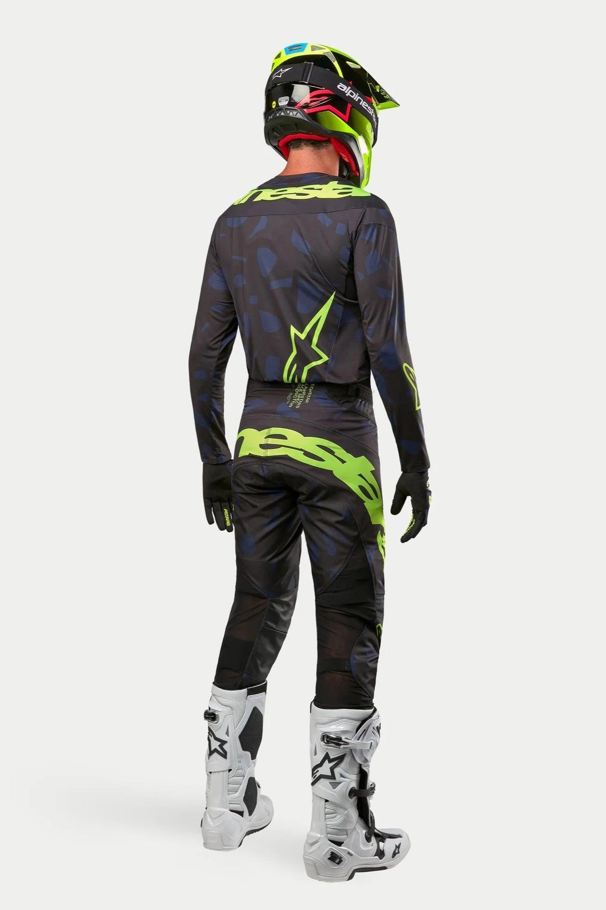 Alpinestars 2024 Techstar Rantera Jersey and Pants, Motocross rider in full gear from the back, Black Navy and Yellow Fluo, matching fluo yellow helmet and white boots, coordinated off-road racing kit