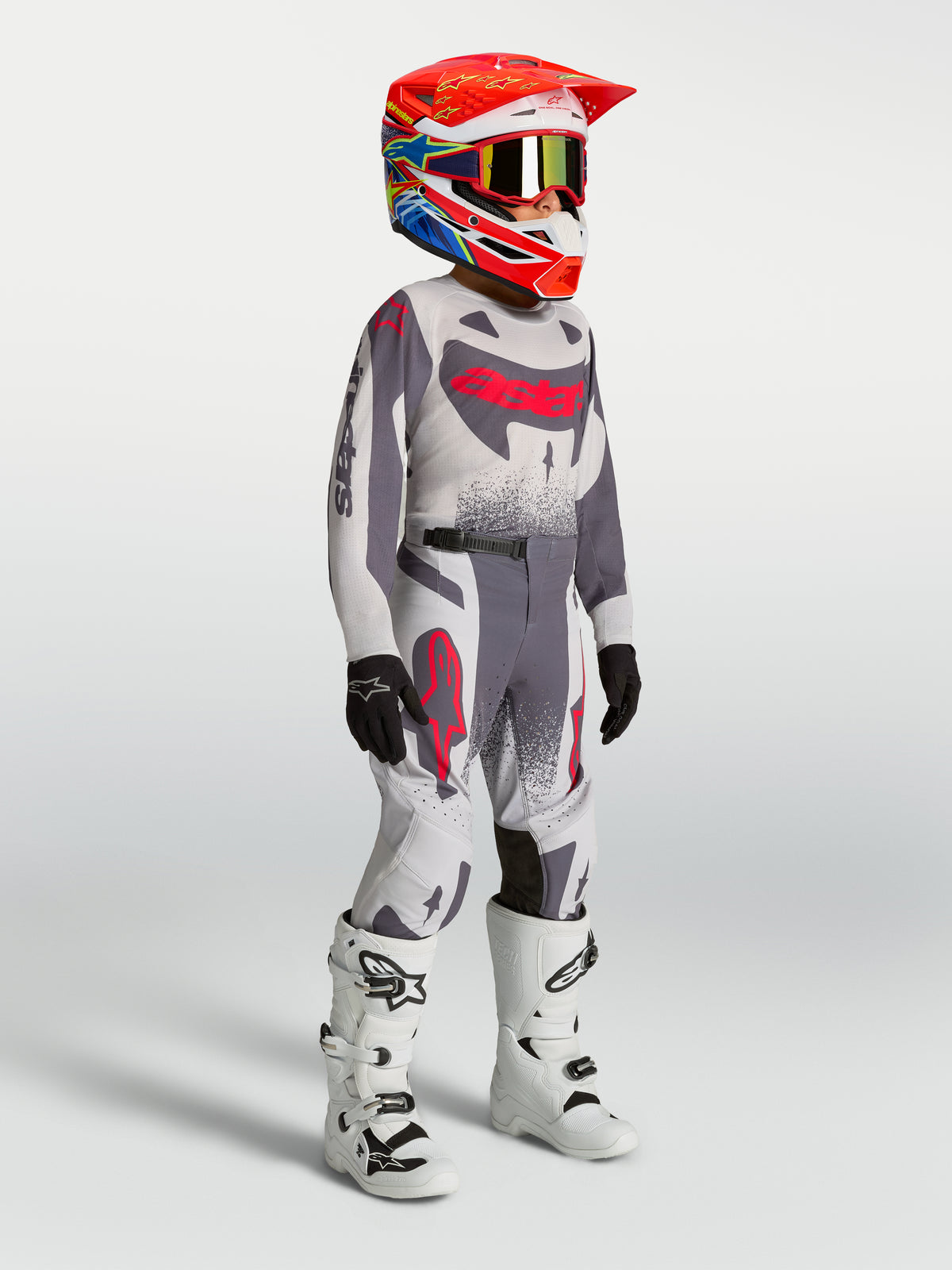 Alpinestars Supertech Swan Jugend-Trikot und Gear Set, Motocross-Outfit in Grau und Leuchtrot mit weißen Rennstiefeln.