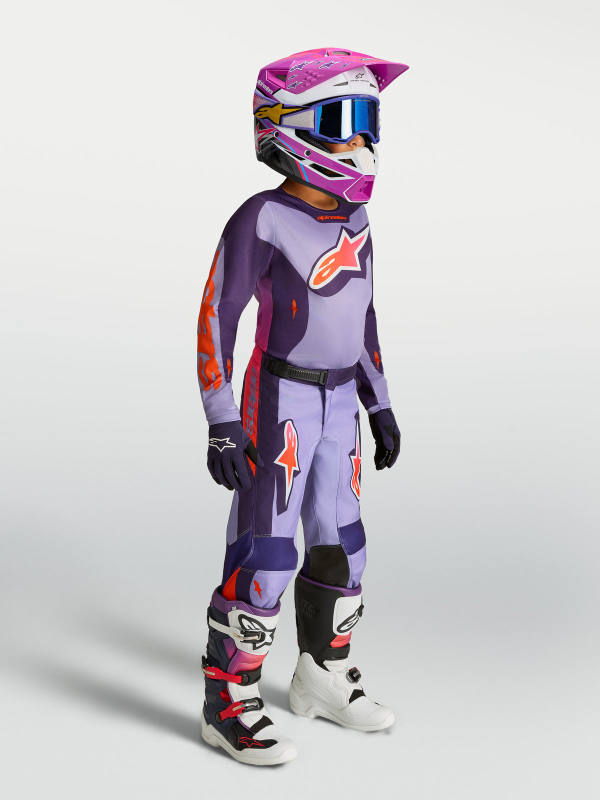 Alpinestars 2027 Youth Fluid Hunt Jersey in purple and pink fluo, youth motocross gear shown on-model with helmet and boots.