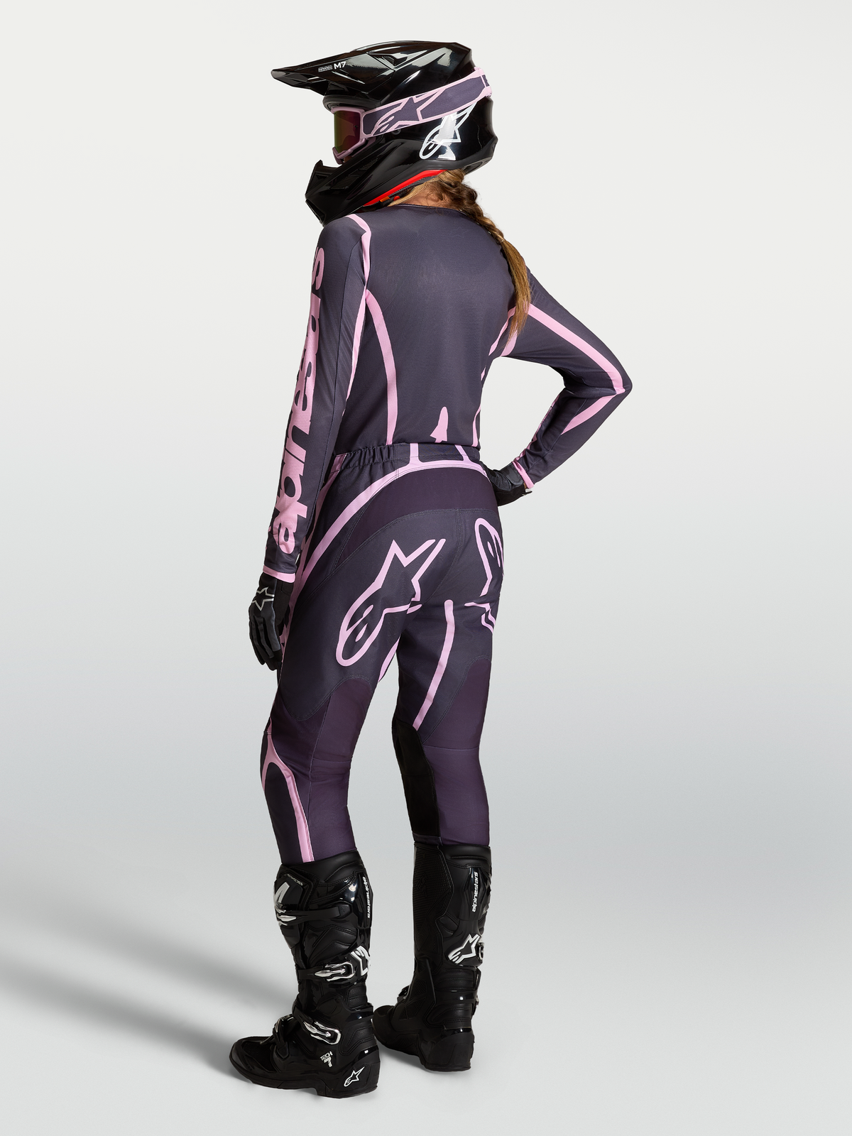 Alpinestars Stella Fluid Apex V2 Trikot und Gear Set, Damen-Motocross-Ausrüstung in Grau und Pink mit schwarzen Stiefeln.