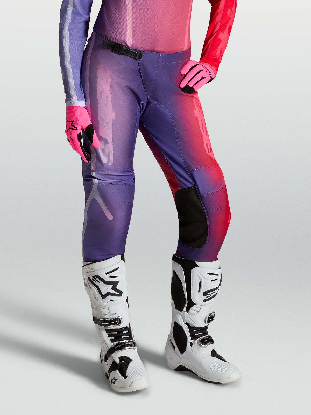 Alpinestars Stella Fluid Kepler Hose, Damen-Motocross-Ausrüstung, Lila und Rot, am Model getragen mit weißen Stiefeln und Handschuhen, strapazierfähige 600D-Polygewebe-Konstruktion.