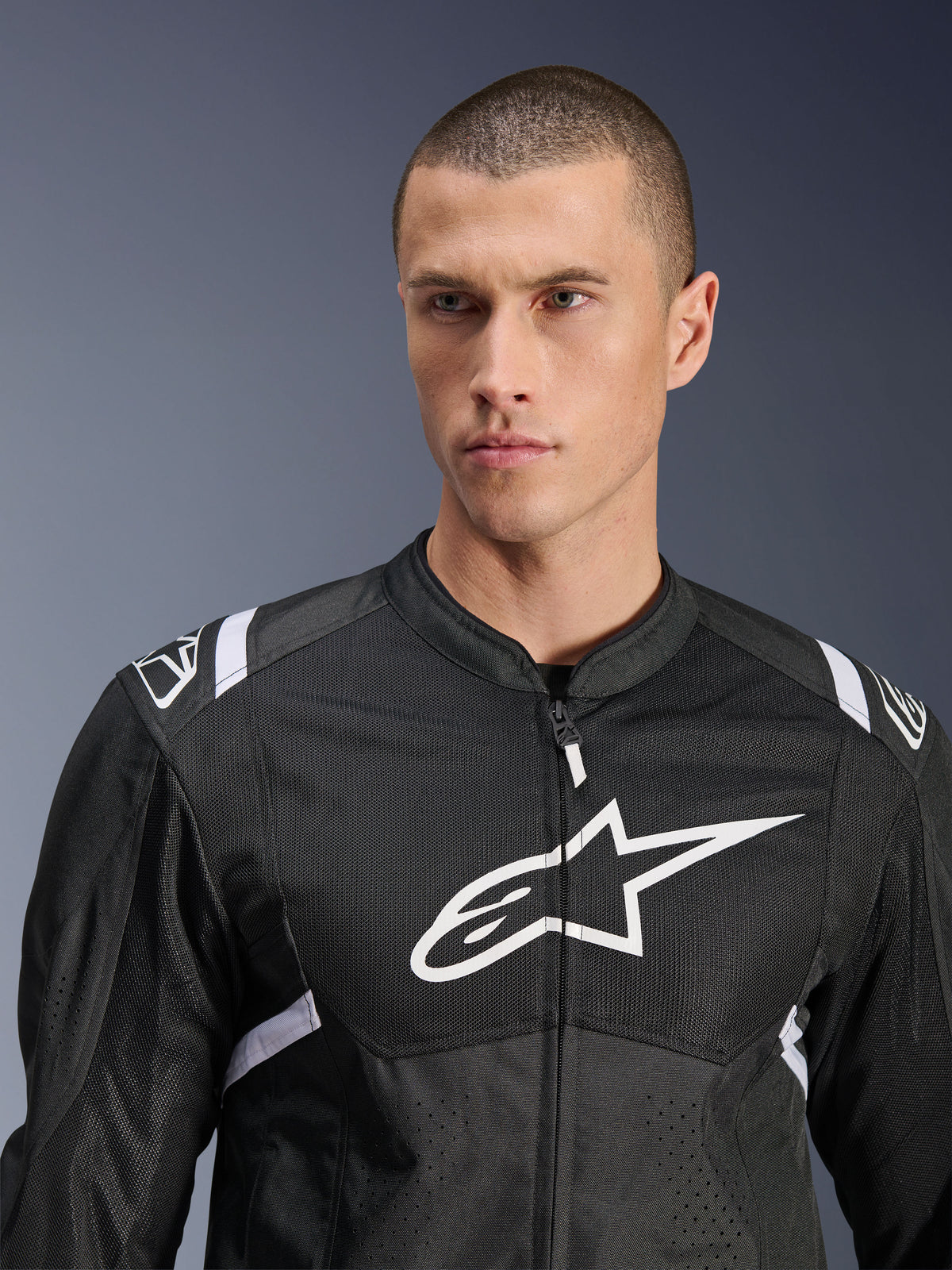 Alpinestars T-SPS Air V2 Jacke, Textil-Motorradjacke, Schwarz und Weiß mit großem weißem Brustlogo und Mesh-Einsätzen, sportliche Performance-Passform, getragen von männlichem Model