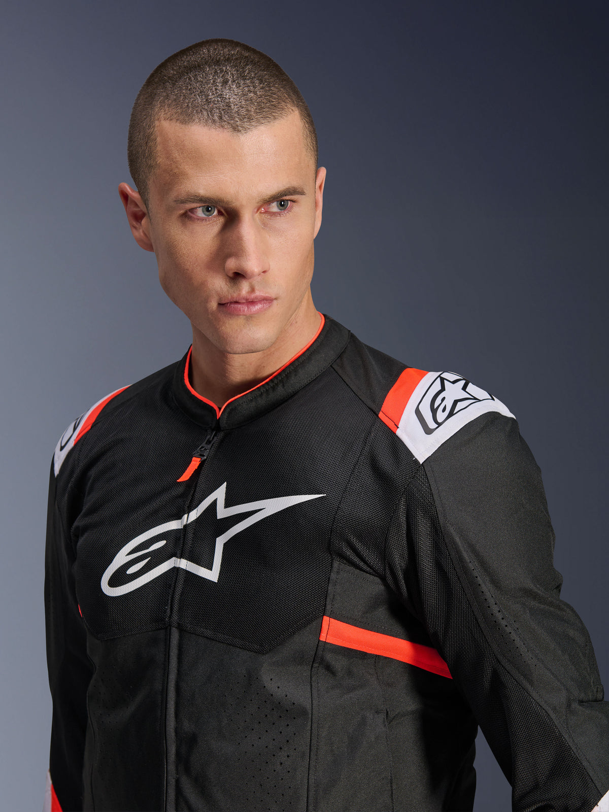 Alpinestars T-SPS Air v2 Jacke, Schwarz mit weißen und neonroten Akzenten, Mesh-Textilkonstruktion für optimale Belüftung, großes weißes Alpinestars-Logo auf der Brust, getragen von einem Modell, urbaner Sport-Fahrstil