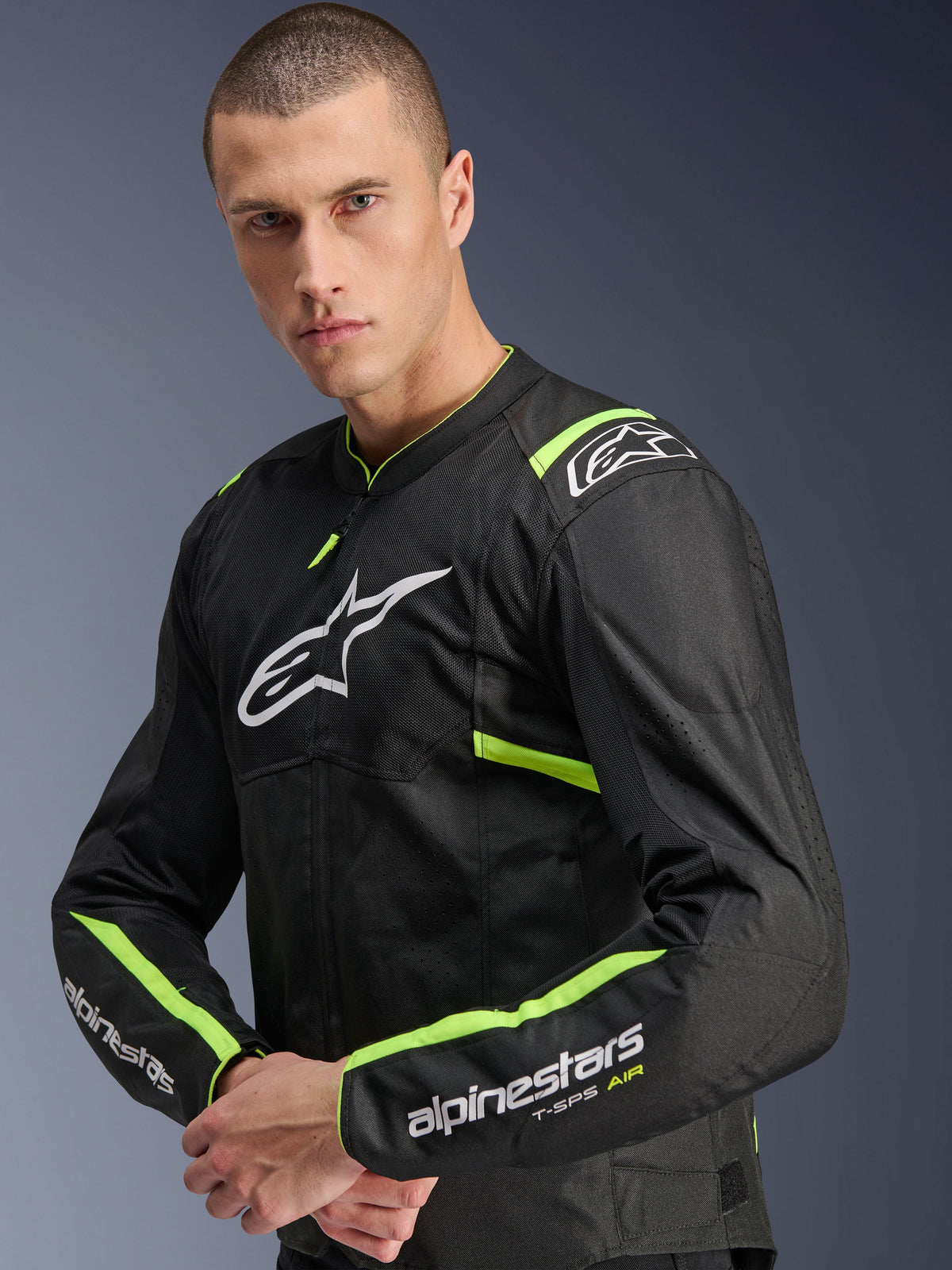 Alpinestars T-Sps Air V2 Jacke, Schwarz Gelb Fluo, Textil-Motorradjacke getragen von einem Modell, Tech-Mesh-Einsätze für Luftzirkulation, weißes Alpinestars-Logo auf der Brust, gelb fluoreszierende Akzente an Schultern und Ärmeln