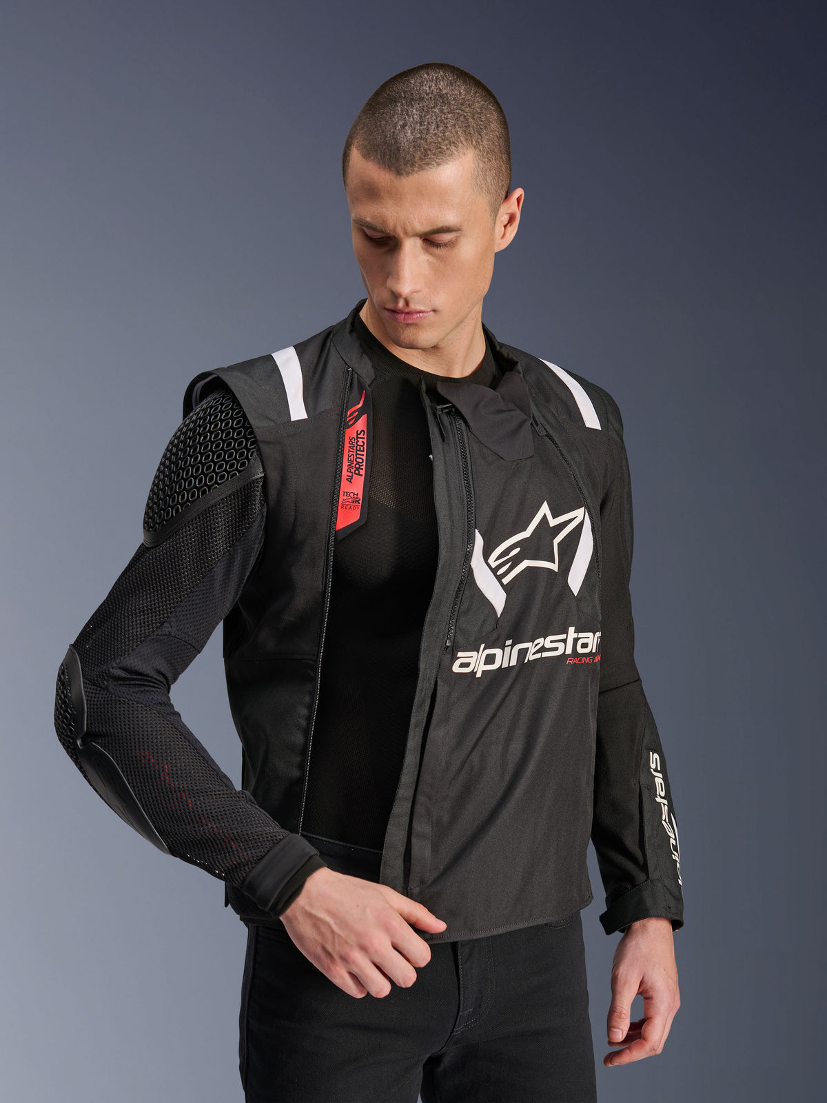 Alpinestars T-Stunt Air Jacke, schwarz-weiße Motorradjacke, getragen von einem männlichen Model, zeigt die modulare Mesh-Konstruktion und sichtbare interne Protektoren an Schulter und Ellbogen, Alpinestars-Branding auf der Brust, Tech-Air® Ready-Funktion, sportlicher Schnitt für den Straßeneinsatz