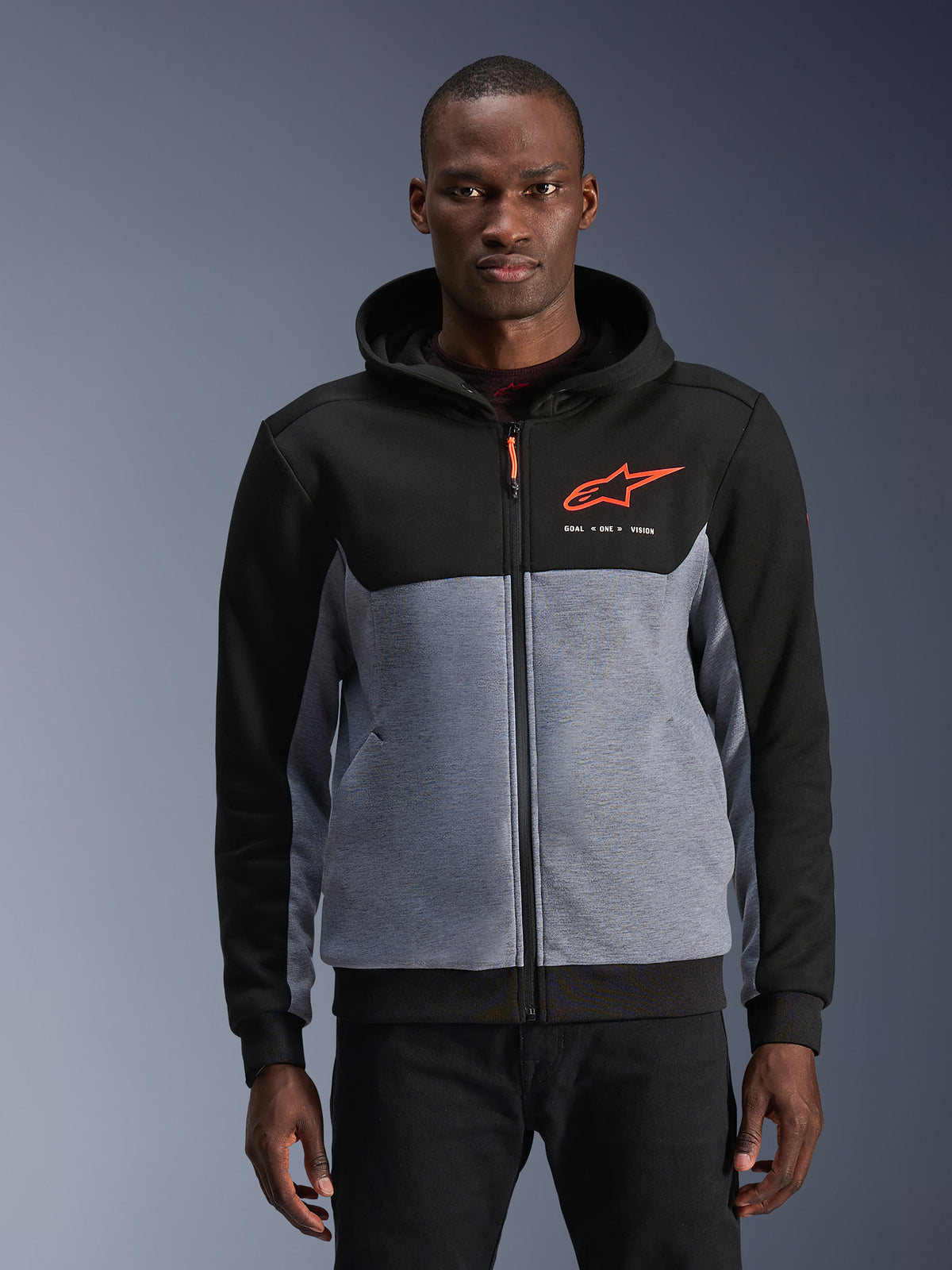 Alpinestars Chrome V2 Sport Kapuzenpullover, urbane Motorradjacke für Herren, Schwarz und Grau meliert mit fluoreszierendem rotem Logo, getragen von einem Model.