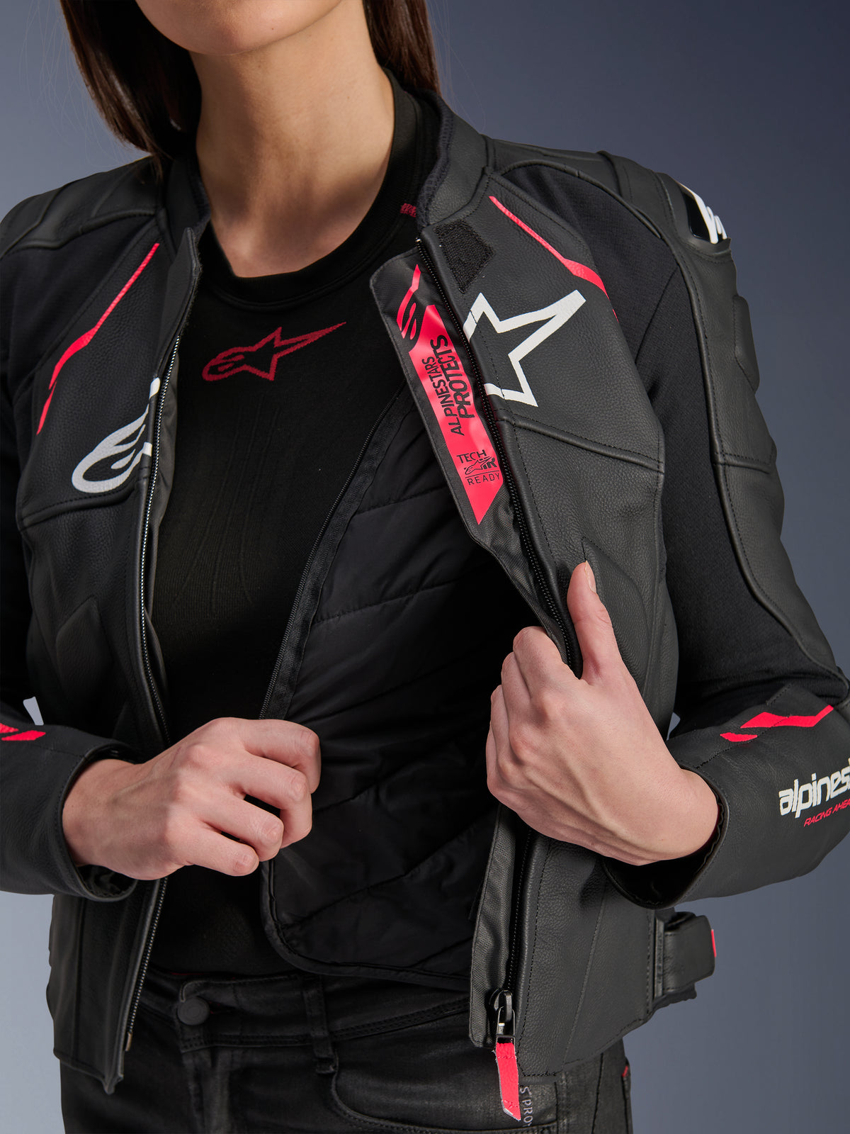 Alpinestars Stella Dusk Damen-Lederjacke, Schwarz, Diva Pink und Weiß, Motorradjacke aus Leder, geöffnet zur Darstellung des gesteppten Thermofutters und des Tech-Air Ready-Brandings, mit weißen Logos und leuchtend pinkfarbenen Akzenten.