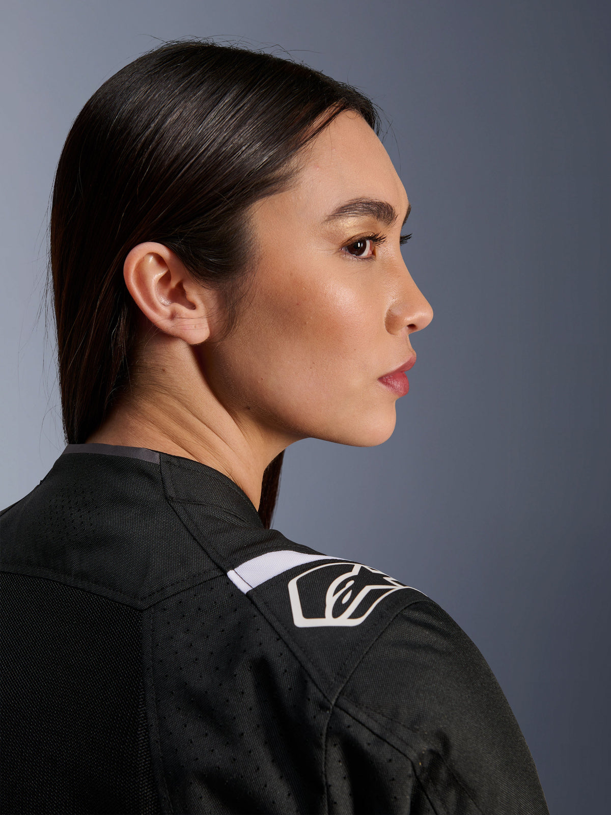 Side profile of a woman wearing the Alpinestars Stella T-Sps Air V2 Jacket in Black and White, close-up view focusing on the shoulder with a white Alpinestars logo and mesh fabric construction for ventilation.