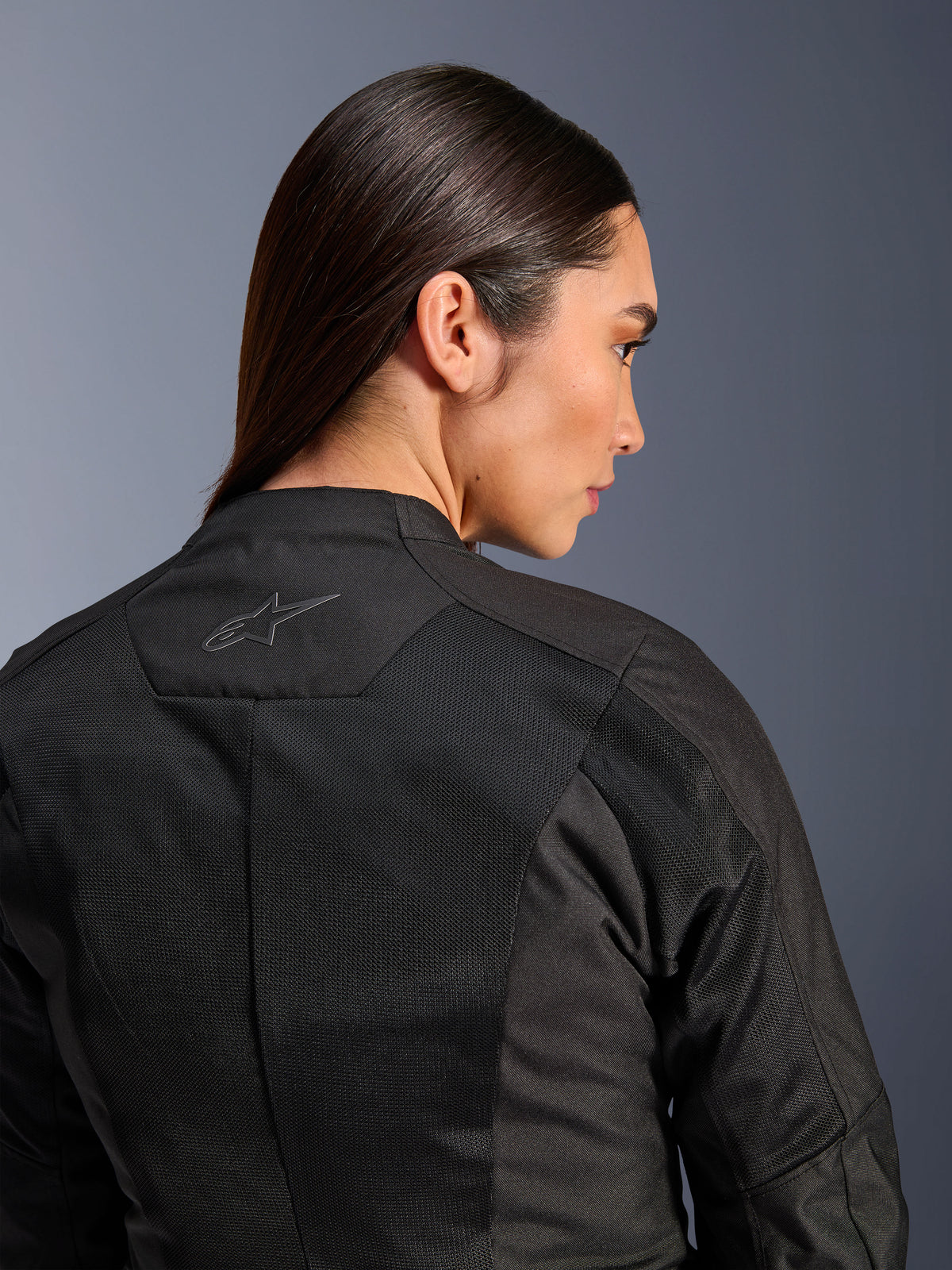 Alpinestars Woman Stella C-1 Air Jacket, Textile Motorcycle Jacket, Black, close-up rear view showing tech mesh ventilation panels and a reflective star logo on the upper back, modern urban riding gear