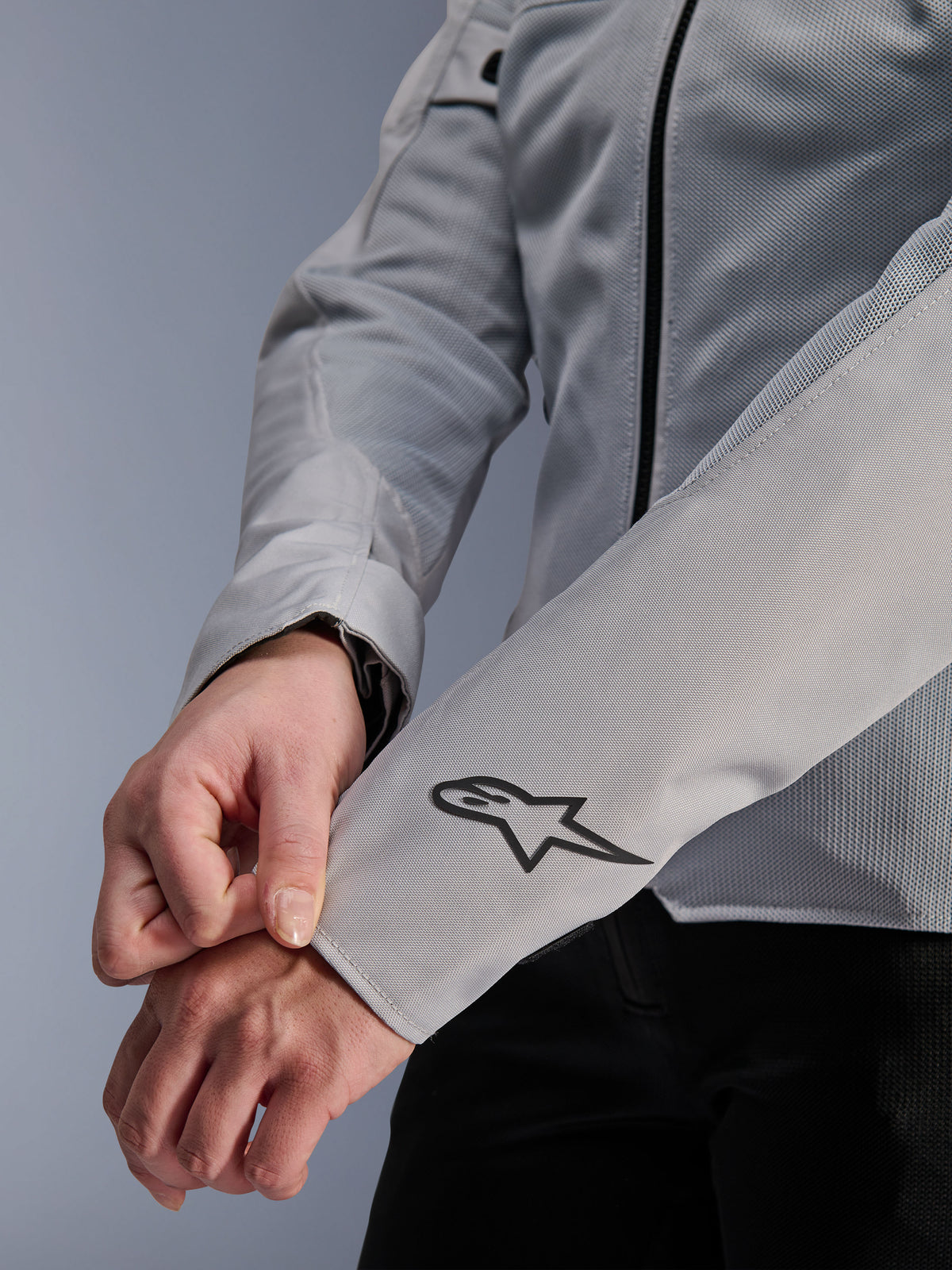 Nahaufnahme der Alpinestars Stella C-1 Air Jacke in Silber, mit technischer Mesh-Konstruktion und schwarzem Alpinestars-Logo am linken Ärmel, urbane Motorradjacke für Damen mit reflektierendem Branding.