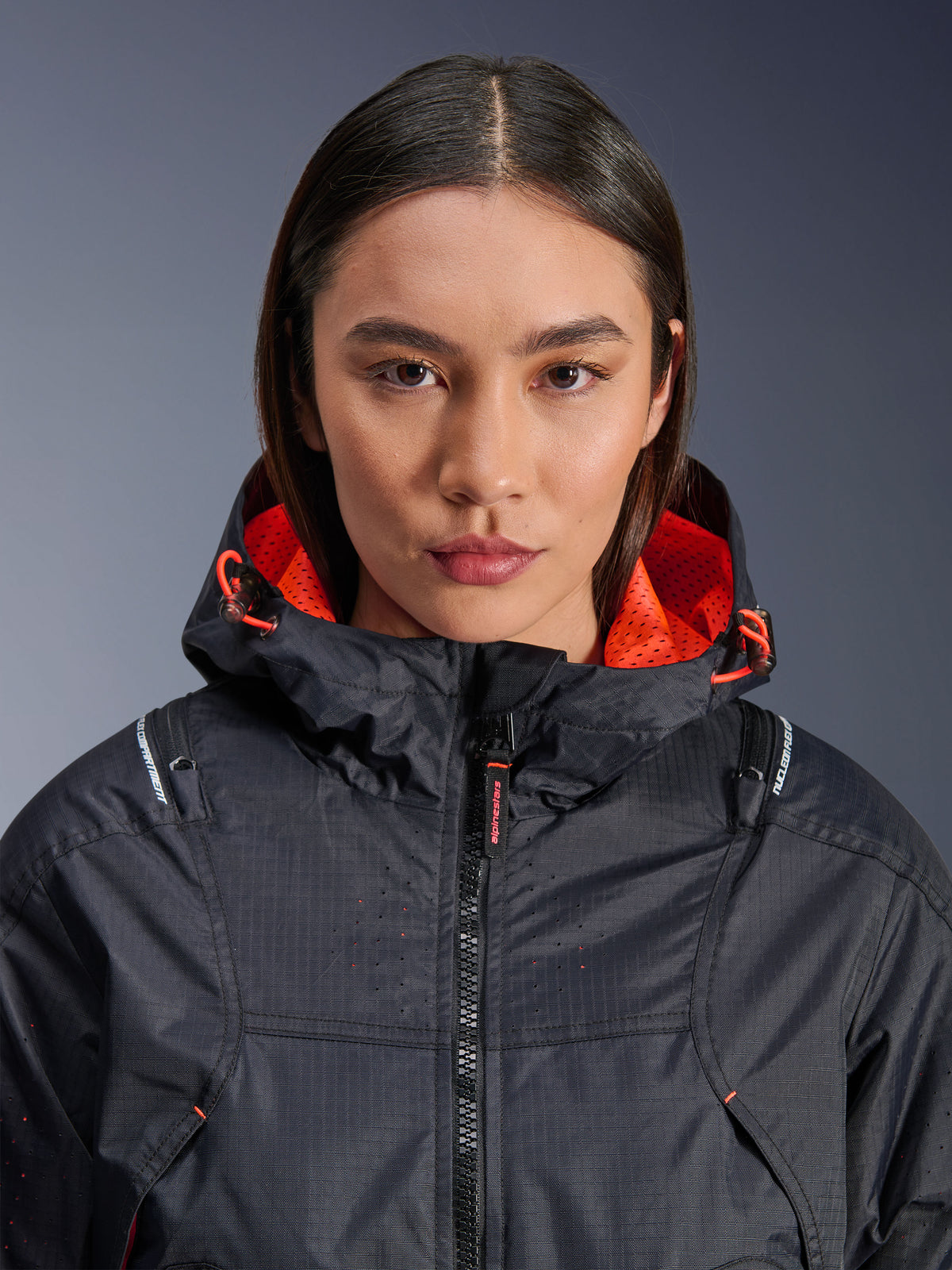 Alpinestars Molly Air Jacke, Motorradjacke für Damen, Schwarz und Fluo Coral, Nahaufnahme der Vorderansicht an einem Model, Ripstop-Textil mit laserperforierter Belüftung, leuchtend oranges Mesh-Kapuzenfutter und Kordelzüge, mit Nucleon Flex Plus Protektoren-Branding