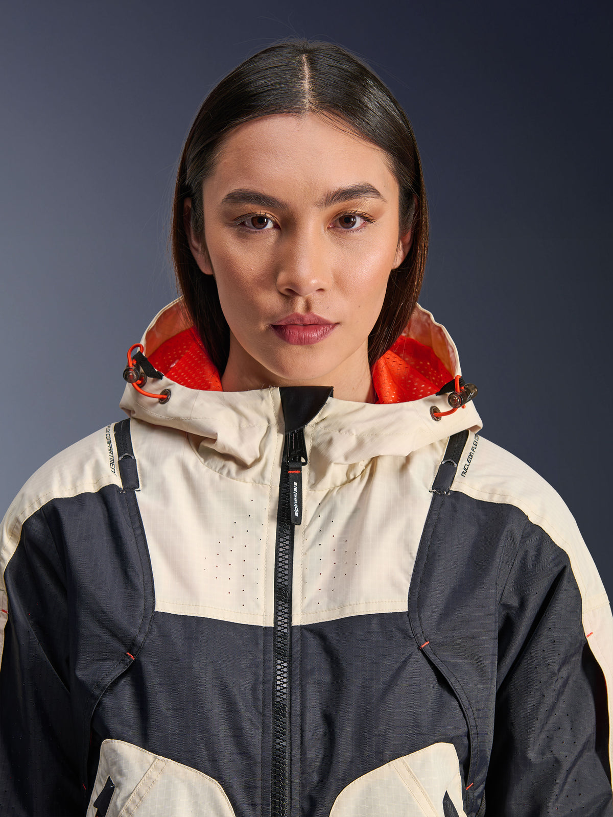 Alpinestars Molly Air Jacket, Women's Textile Motorcycle Jacket, Black Almond, close-up front view of a model wearing the jacket with a cream and black paneled design, bright orange mesh-lined hood, and laser-perforated detailing on the chest