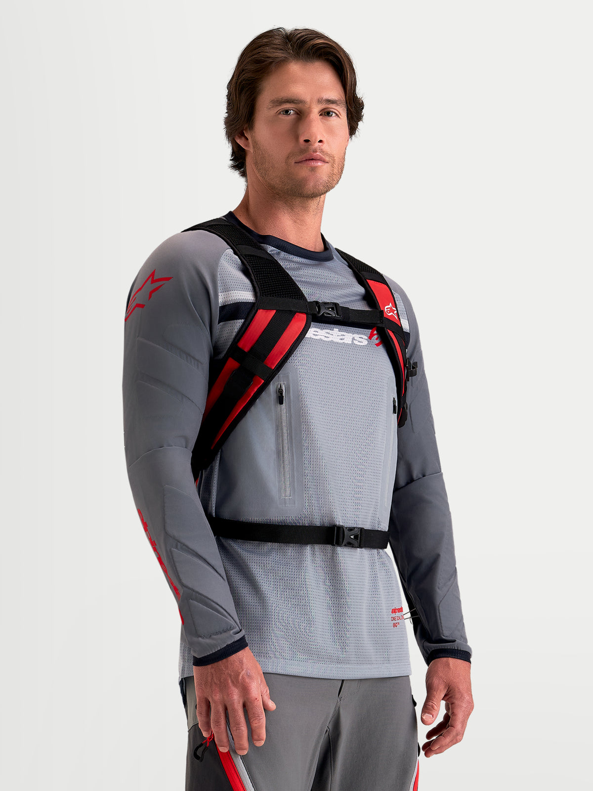 Alpinestars AT-9 Backpack, motocross backpack in black and bright red, worn by a model showcasing the padded harness and secure closure system