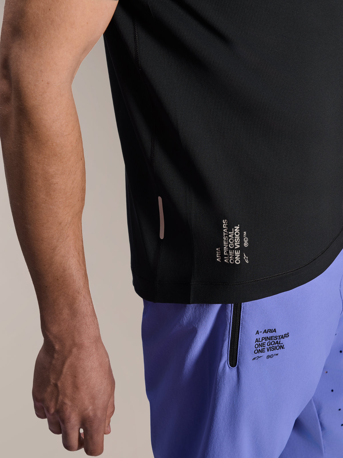 Alpinestars A-Aria Lite Shorts in Baja Blue, MTB-Shorts, mit Siebdruck-Branding „One Goal. One Vision.“ und Reißverschlusstasche, kombiniert mit einem schwarzen A-Aria Switch Trikot, Nahaufnahme von technischer Fahrradausrüstung.