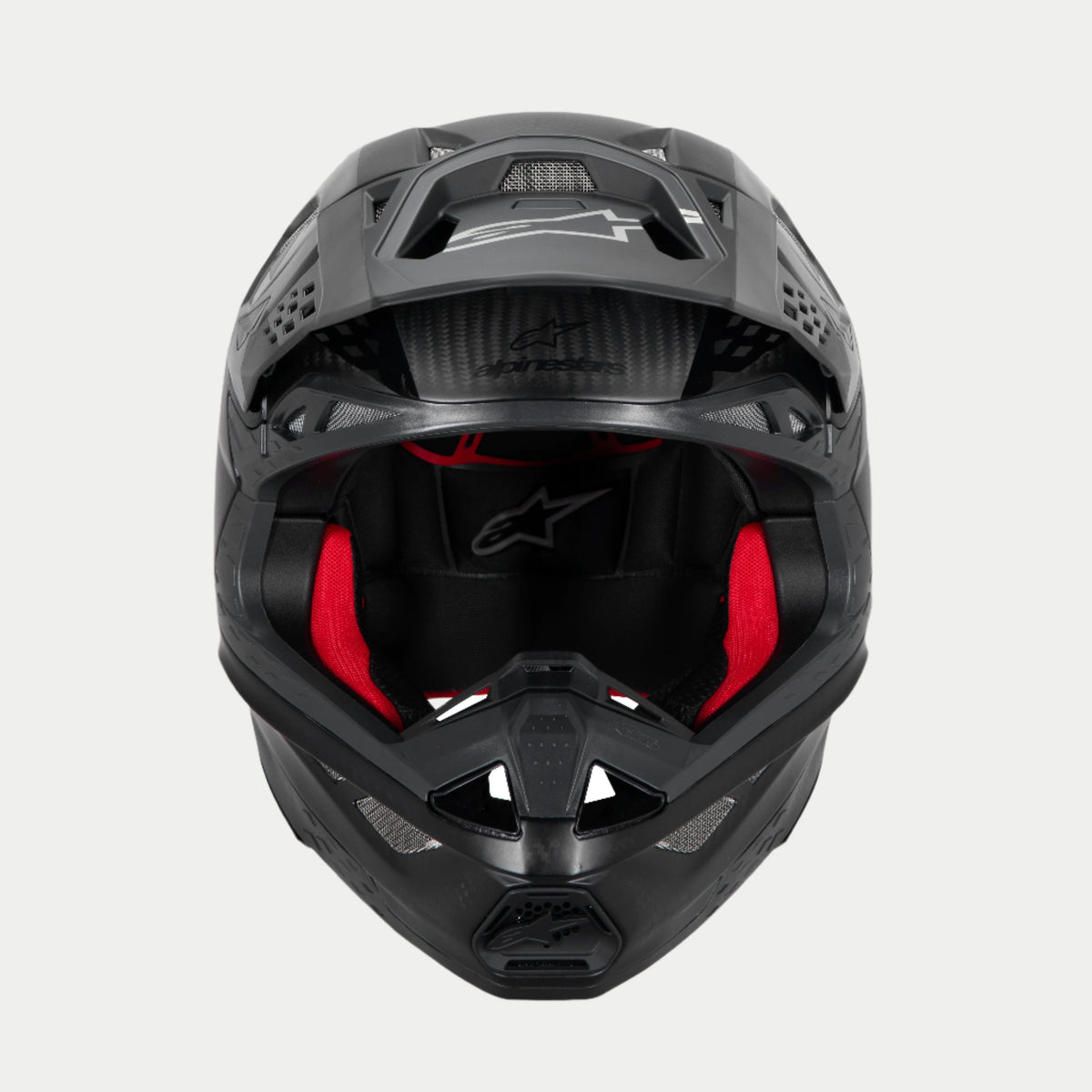 Alpinestars Supertech M10 Fame ECE 22.06 Helm, Motocross-Helm, Schwarz Carbon Matt und Glänzend, Frontansicht mit sichtbarer roter Innenpolsterung, aerodynamische Carbonfaserschale, belüftetes Design für den Offroad-Rennsport