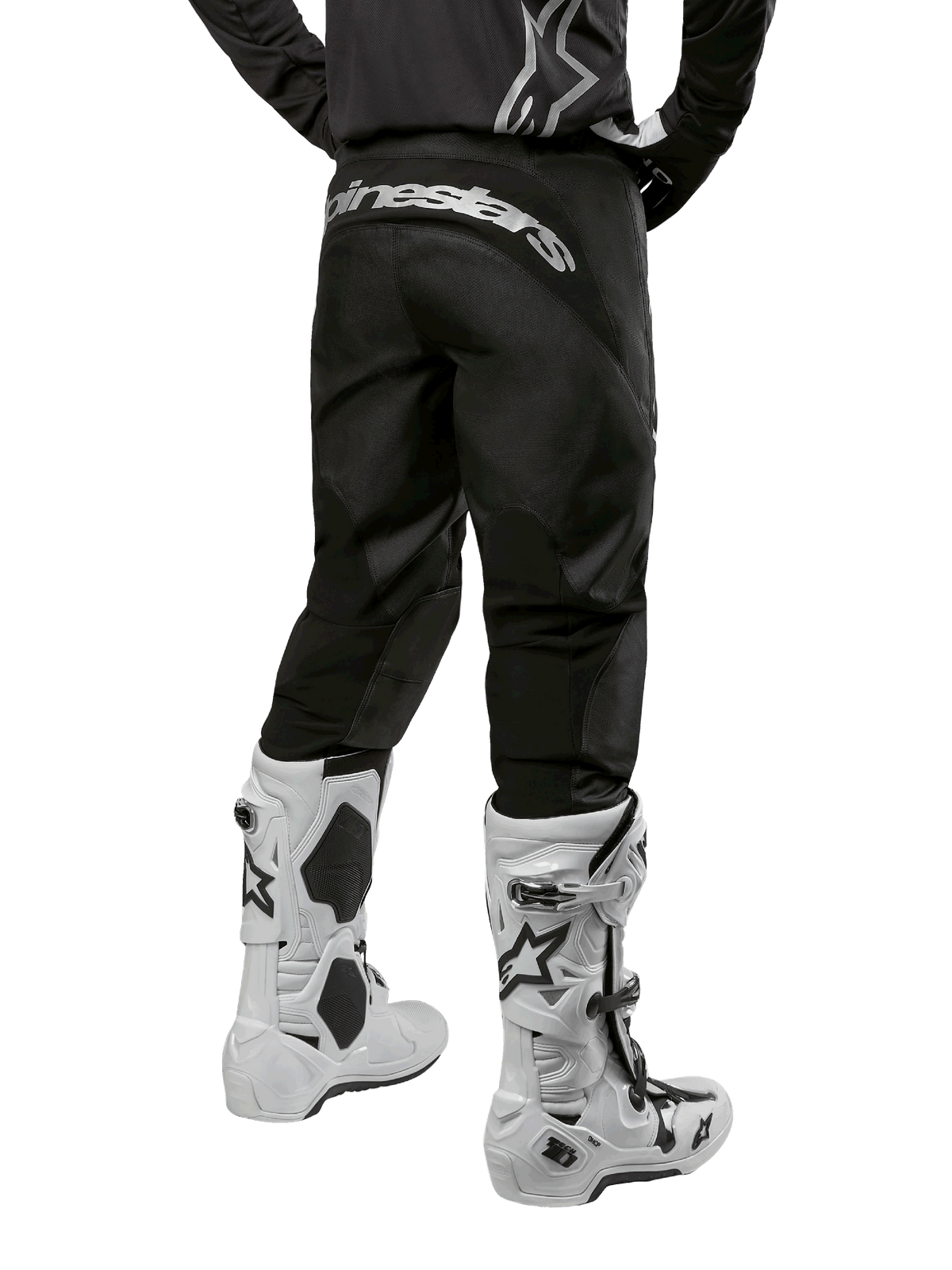 Alpinestars 2024 Fluid Graphite Ausrüstungsset, Rückansicht der schwarz-grauen Motocross-Hose mit weißem Alpinestars-Branding am Gesäß, weiße und schwarze Motocross-Stiefel, spezialisierte Offroad-Rennausrüstung