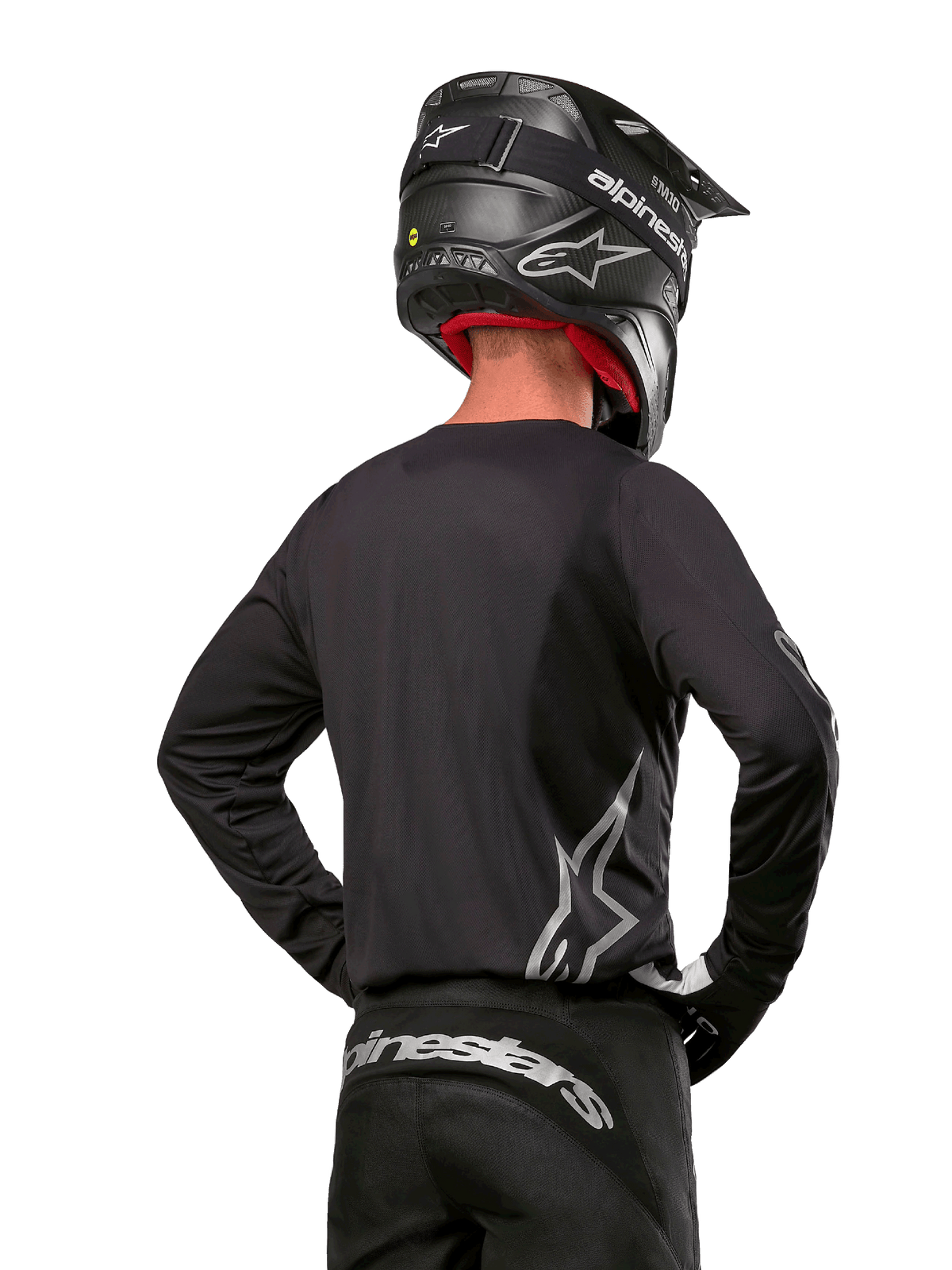Alpinestars 2024 Fluid Graphite Ausrüstungsset, Motocross-Trikot und -Hose, Graphit und Silber, Rückansicht mit silbernem Branding am unteren Rücken und an der Taille, getragen mit schwarzem Helm in Carbon-Optik, leichtes Poly-Gewebe-Design für Offroad-Fahrten