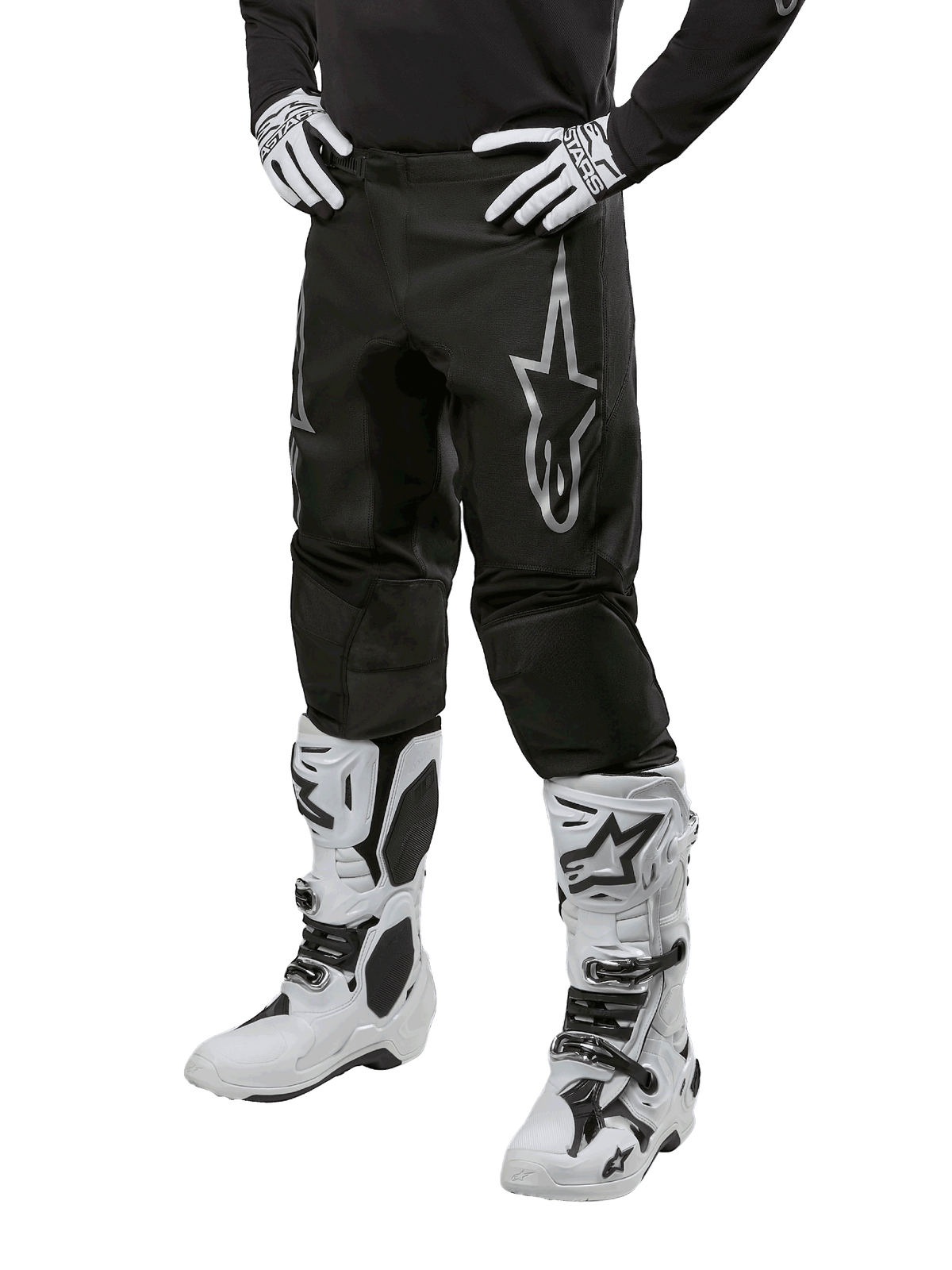 Alpinestars 2024 Fluid Graphite Hose, Motocross-Hose, Grau und Schwarz, kombiniert mit weiß-schwarzen Motocross-Stiefeln und Handschuhen, mit großem silbernen Alpinestars-Logo am Oberschenkel, sportlich-athletische Passform für Offroad-Fahrten