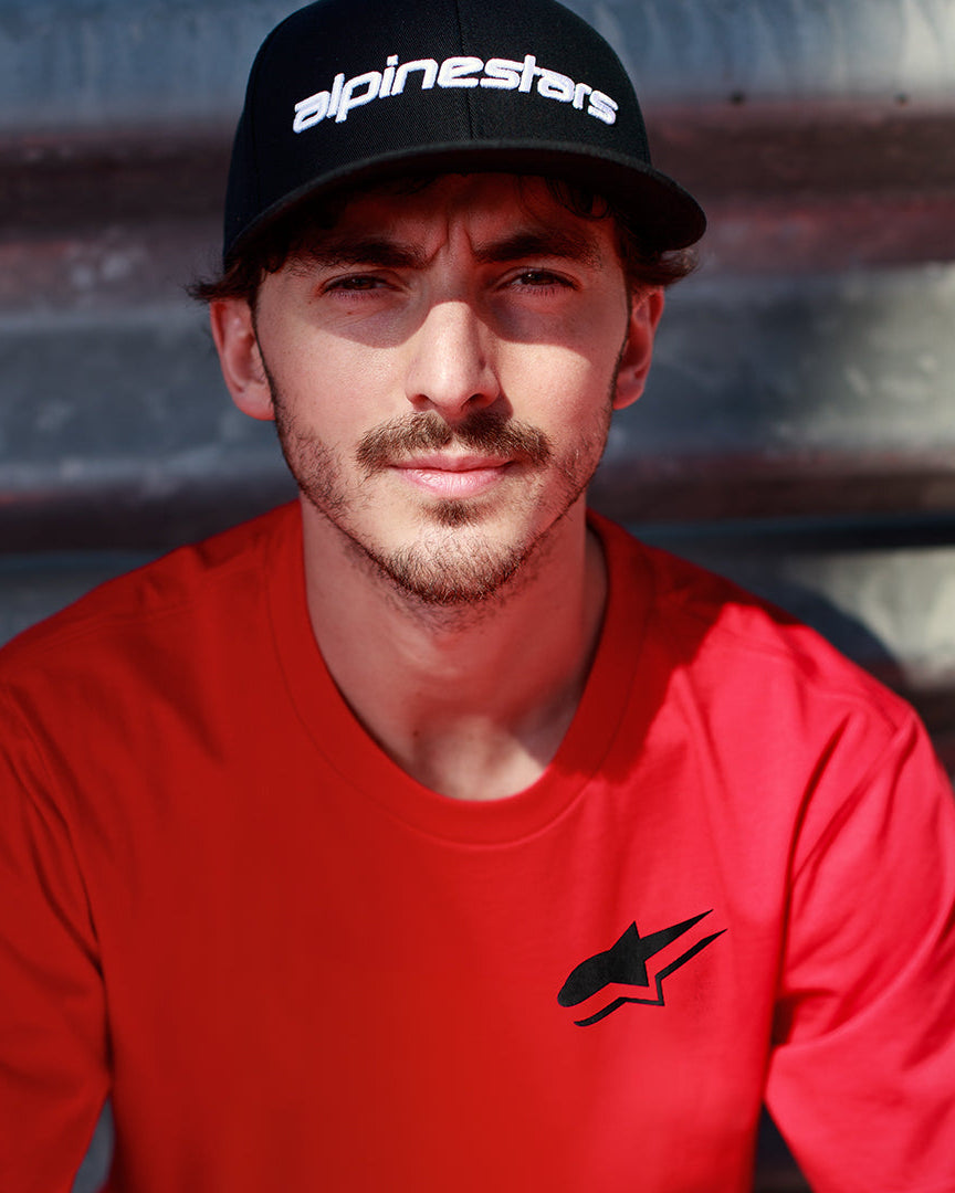 Alpinestars Formulate Csf T-Shirt in Rot, Francesco Bagnaia trägt ein kurzärmeliges T-Shirt mit schwarzem Astars-Logo und schwarzer Baseballkappe, lässige Motorsport-Streetwear