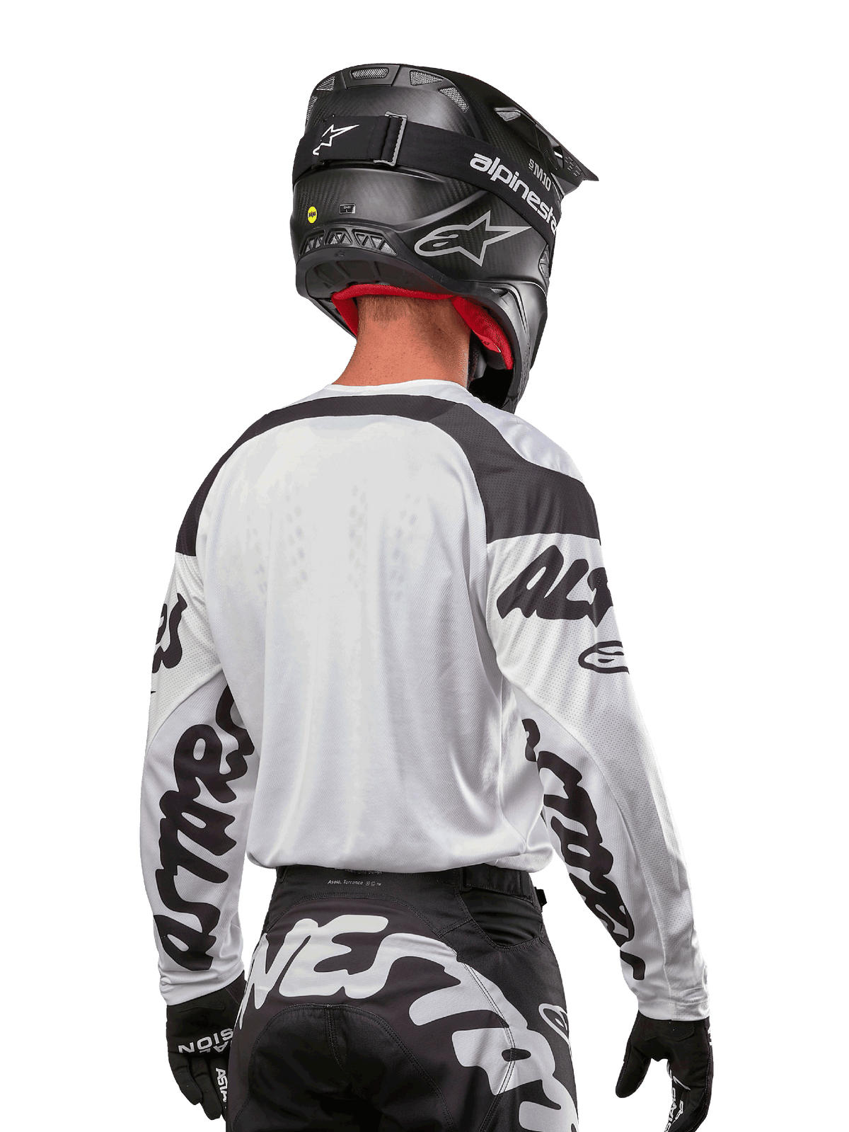 Alpinestars 2024 Racer Hana Trikot, Weiß und Schwarz, Rückansicht zeigt ergonomische Passform und markantes Ärmel-Branding, kombiniert mit einem schwarzen Motocross-Helm und dazu passender schwarz-weißer Hose, Hochleistungs-Rennausrüstung für Offroad-Fahrten