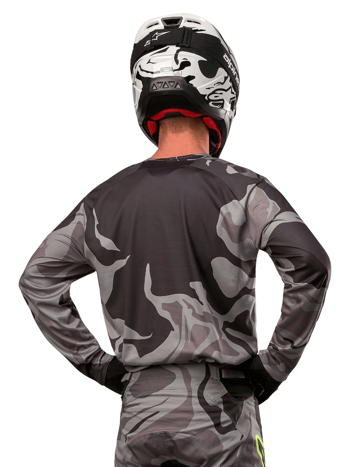 Alpinestars 2024 Racer Tactical Trikot, Motocross-Trikot, Cast Gray Camo Magnet, Rückansicht mit grauem und schwarzem Tarnmuster, getragen mit passender Hose und einem schwarz-weißen Helm, professionelle Offroad-Rennausrüstung