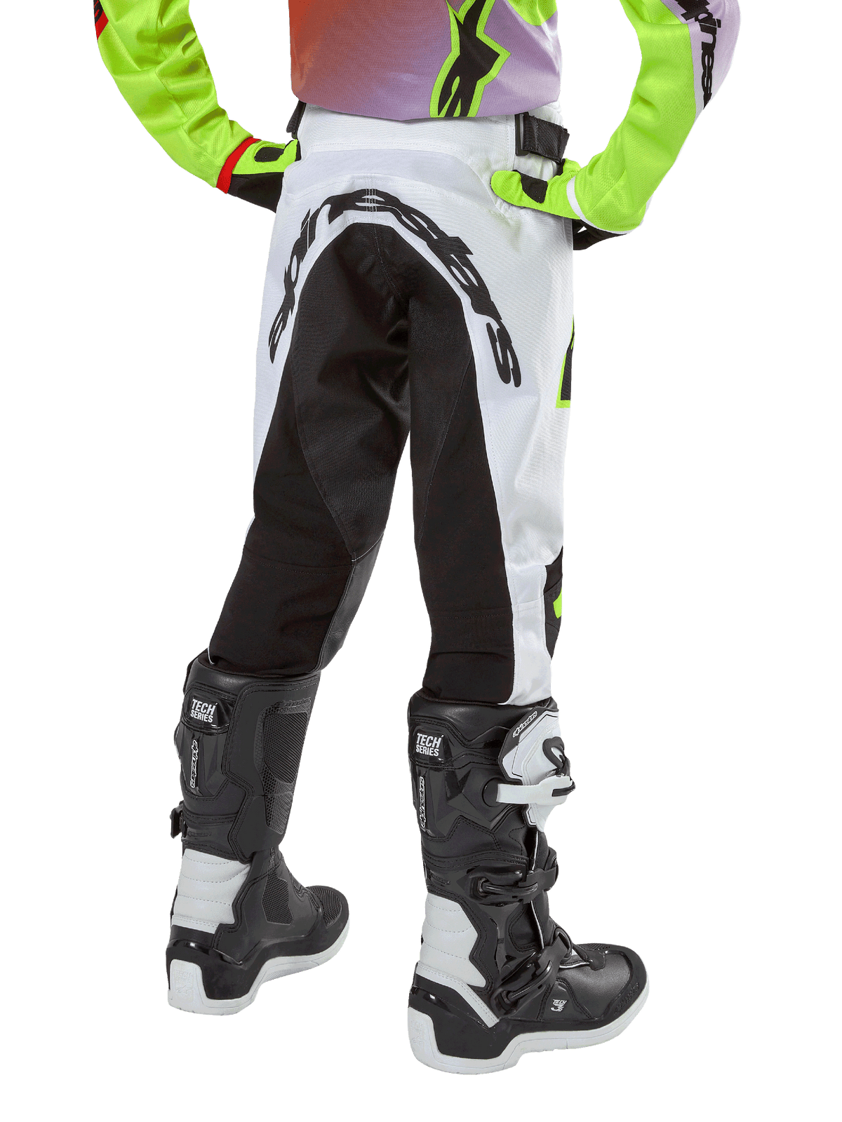 Alpinestars Youth 2024 Racer Lucent Hose, Motocross-Hose, Weiß und Schwarz mit Neon-Akzenten, Rückansicht mit großem hinterem Stretch-Panel und Alpinestars-Logo, kombiniert mit schwarz-weißen Alpinestars Tech Series Stiefeln.
