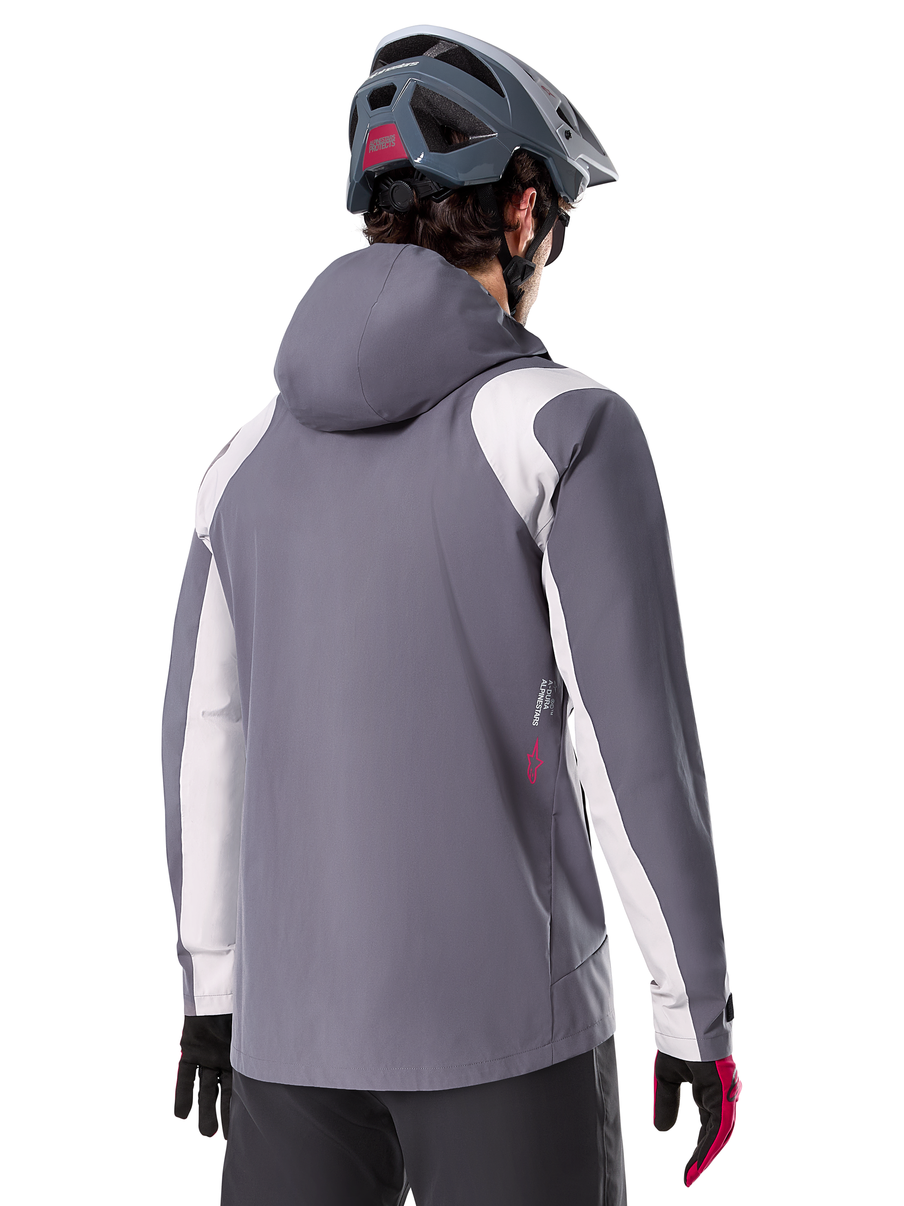 Alpinestars A-Dura Regenjacke, Mountainbike-Jacke, Dunkles Titangrau, Rückansicht mit hellgrauen Schulter- und Armeinsätzen, rotes Logo-Detail an der Seite, getragen mit einem grauen MTB-Helm und schwarz-roten Handschuhen, technische Trail-Bekleidung