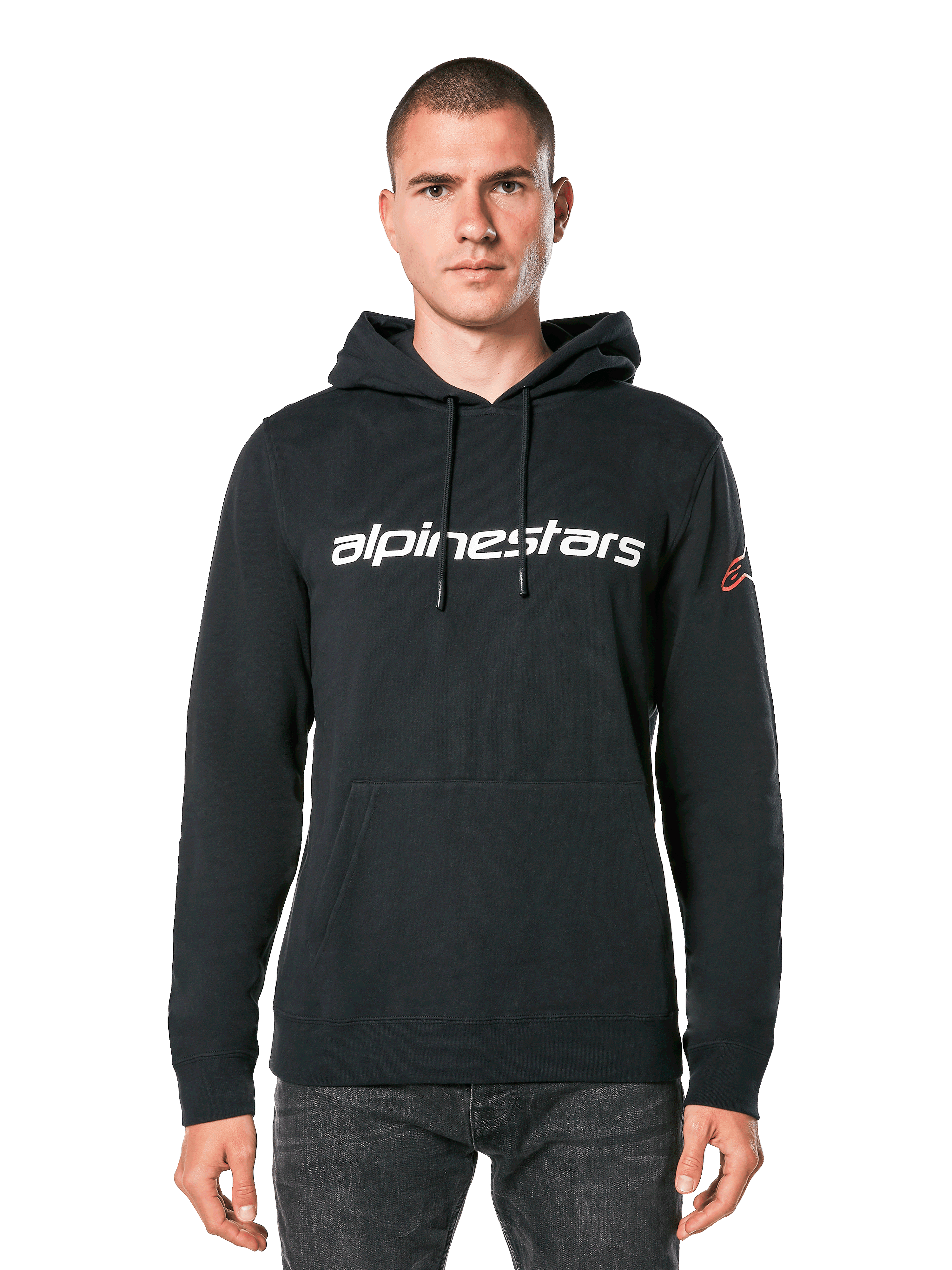 Alpinestars Linear Wordmark V3 Hoodie, schwarzer Kapuzenpullover, weißer Alpinestars-Schriftzug auf der Brust, rotes Ageless-Logo am Ärmel, Kängurutasche vorne, Kapuze mit Kordelzug, getragen von einem männlichen Model, lässige, vom Motorsport inspirierte Streetwear